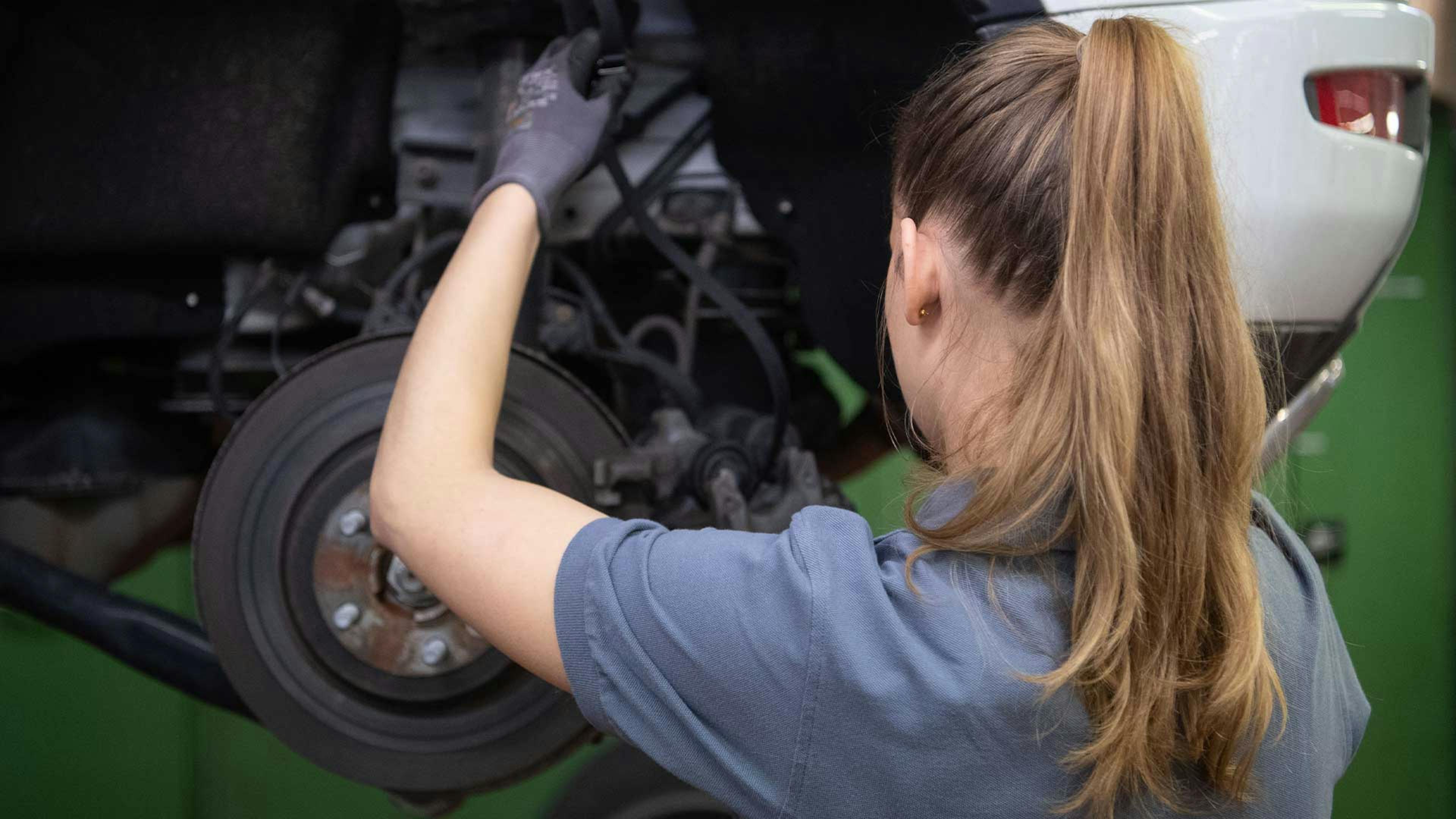Eine Mechanikerin wechselt die Bremsscheibe eines Range Rover Evoque