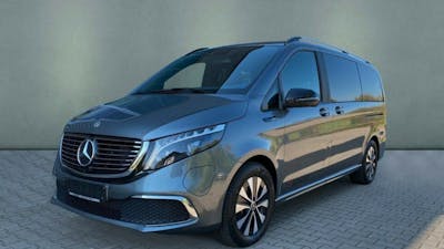 Ein grauer Mercedes-Benz EQV steht vor einer grauen Wand.
