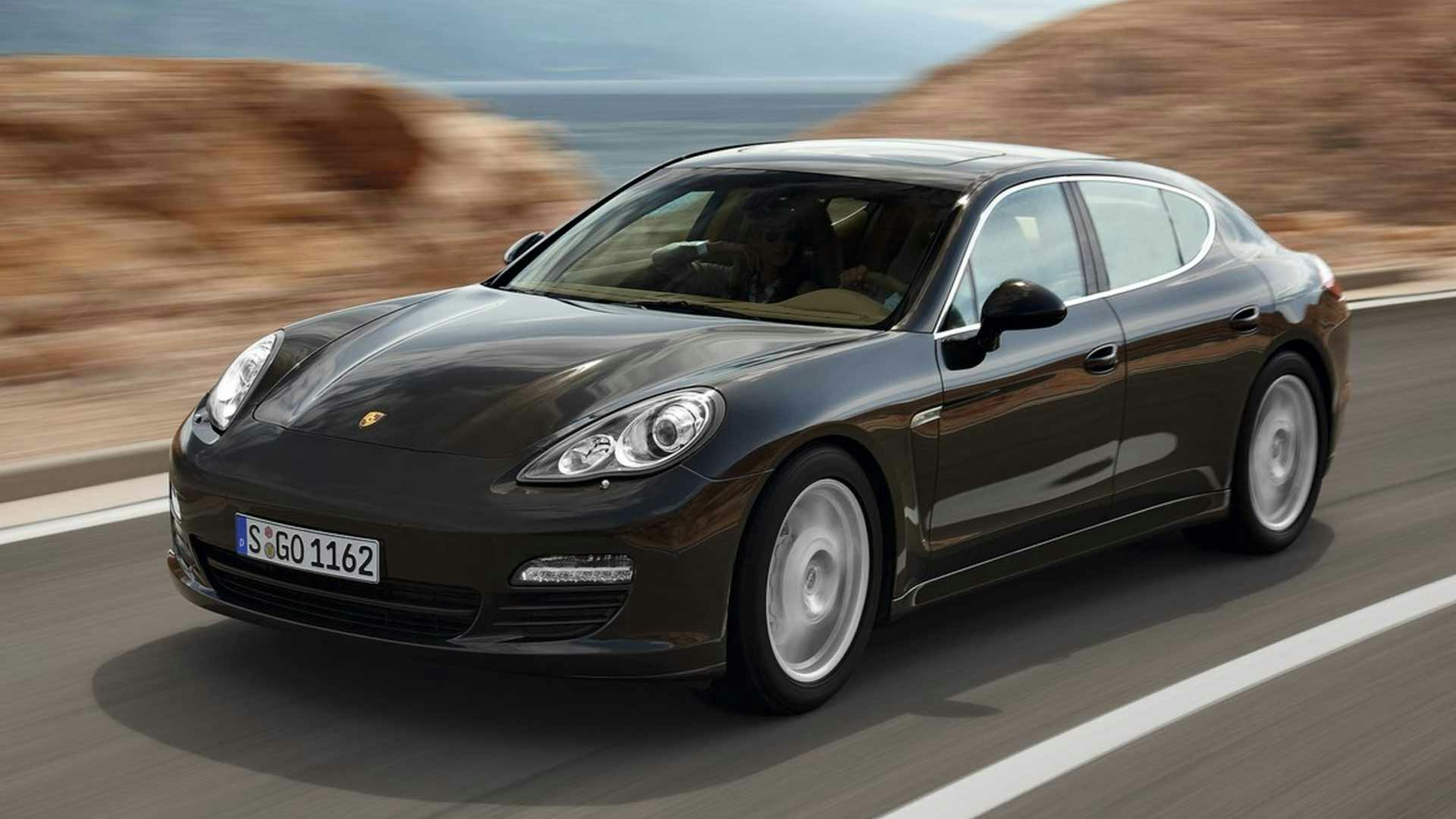 Ein schwarzer Porsche Panamera der ersten Generation fährt eine Landstraße entlang.