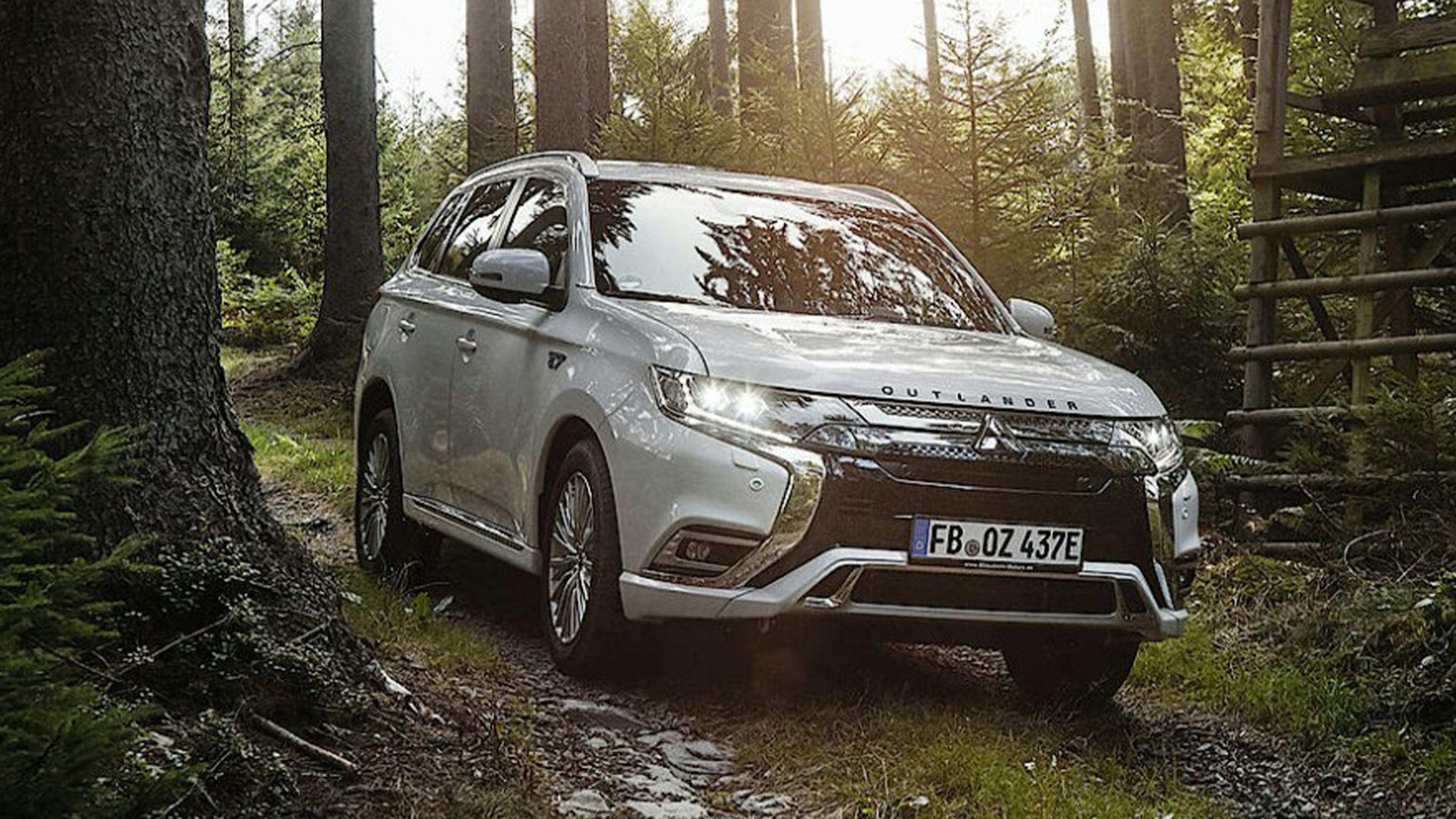 Ein hellgrauer Mitsubishi Outlander fährt durch einen Wald