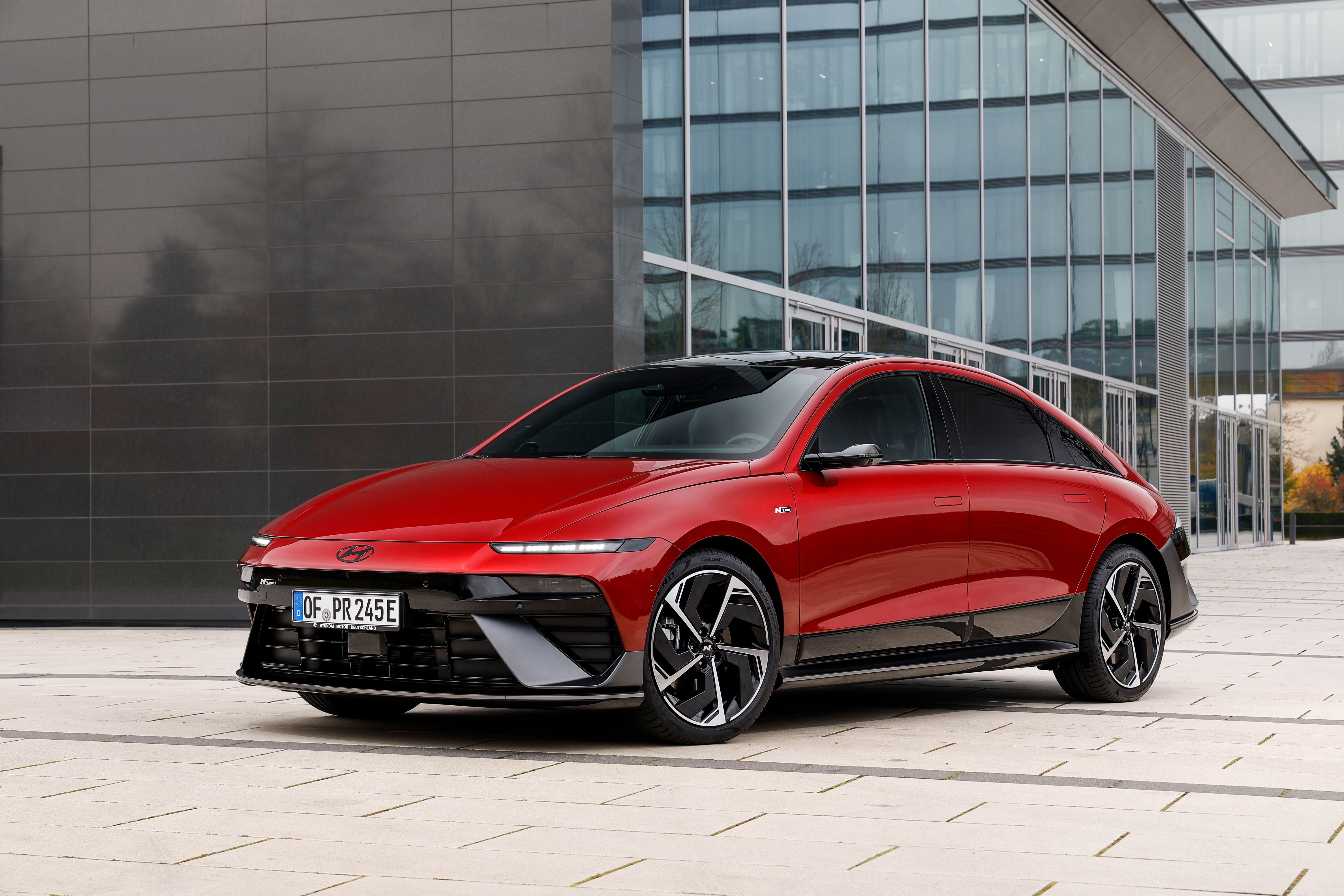 Ein roter Hyundai Ioniq 6 steht vor einem modernen Gebäude.