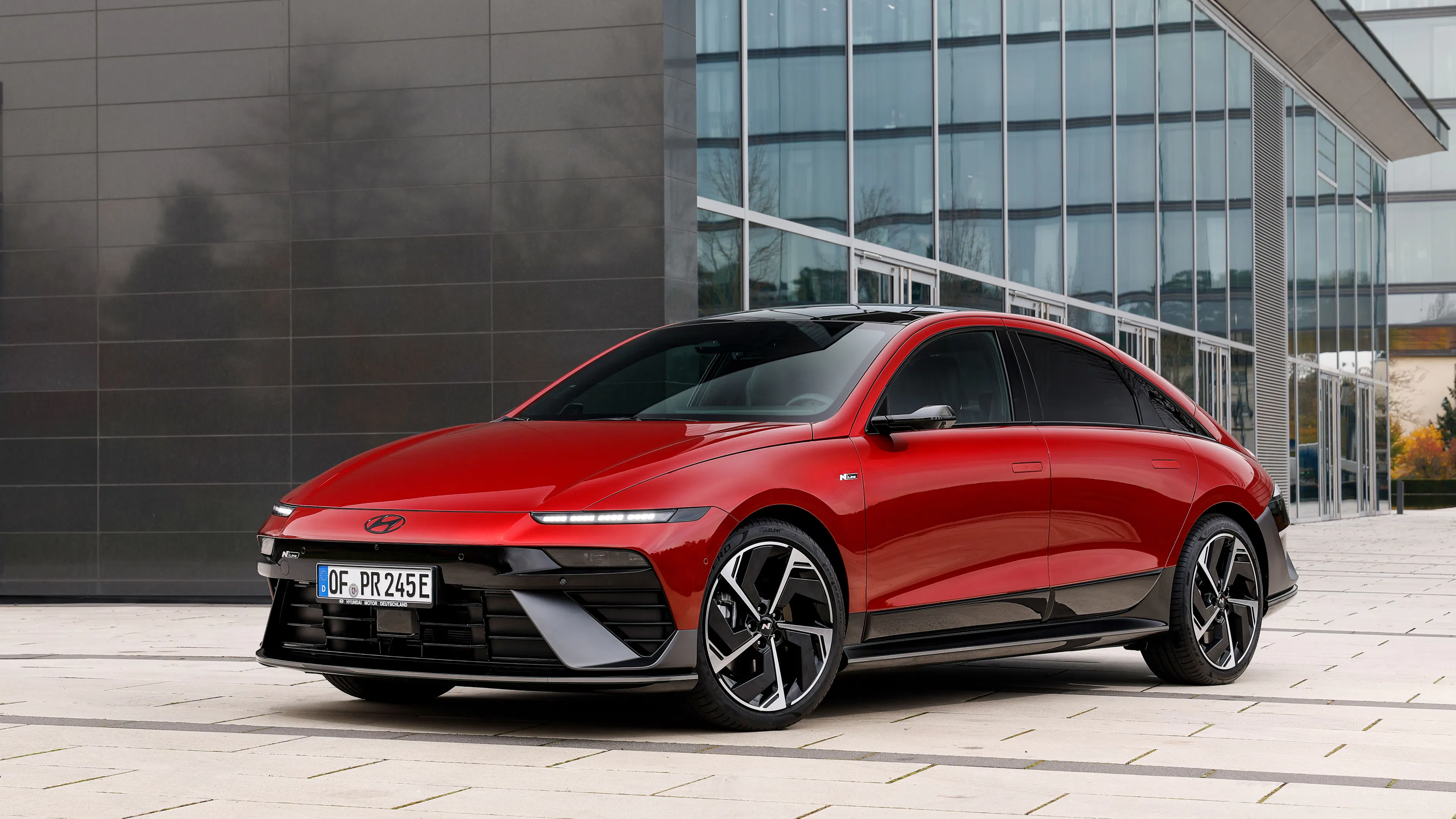 Ein roter Hyundai Ioniq 6 steht vor einem modernen Gebäude.
