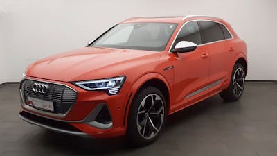 Ein roter Audi e-tron quattro steht vor einer weißen Wand.