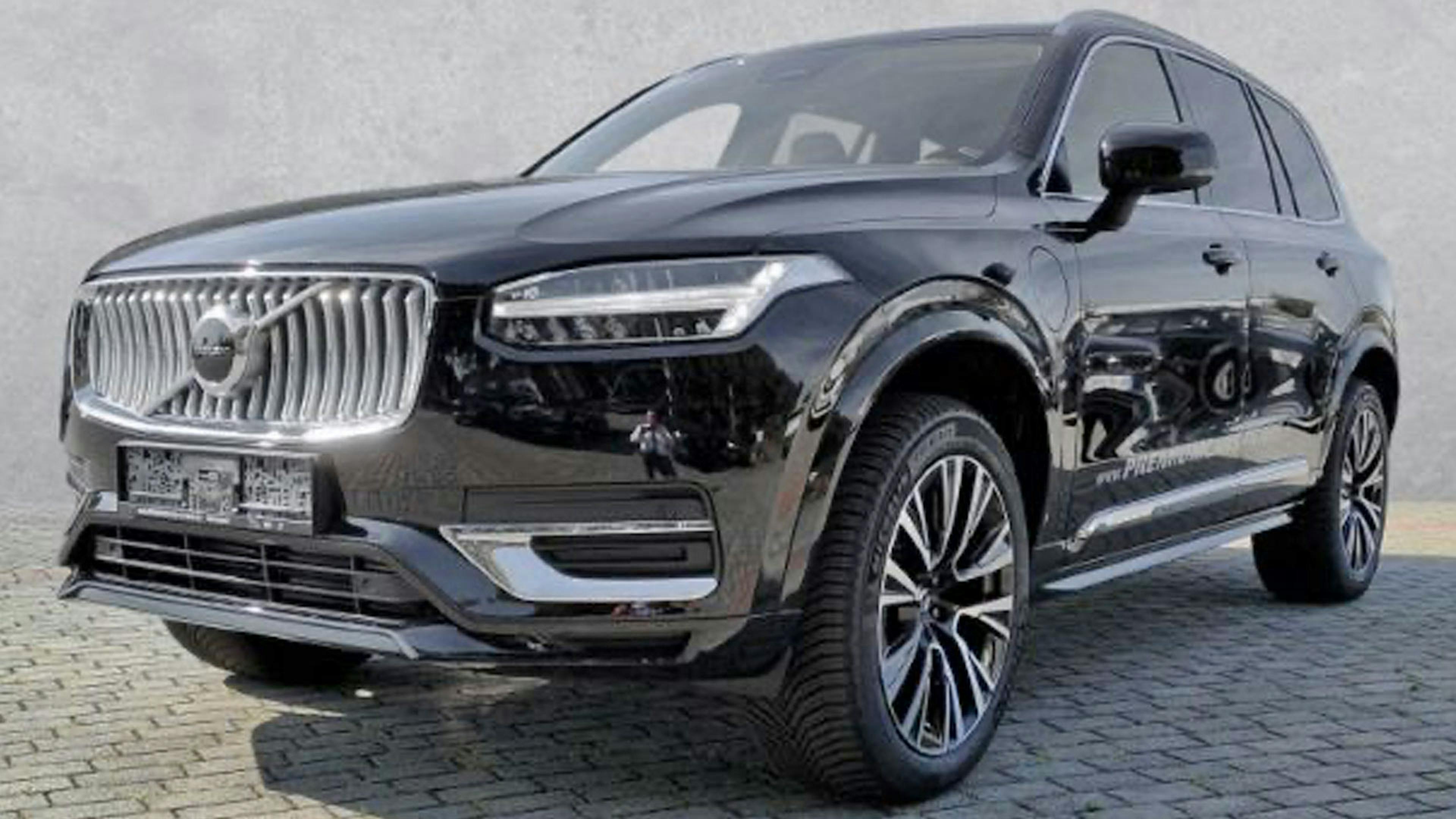 Ein schwarzer Volvo XC90 T8 Recharge AWD steht vor einer grauen Wand.