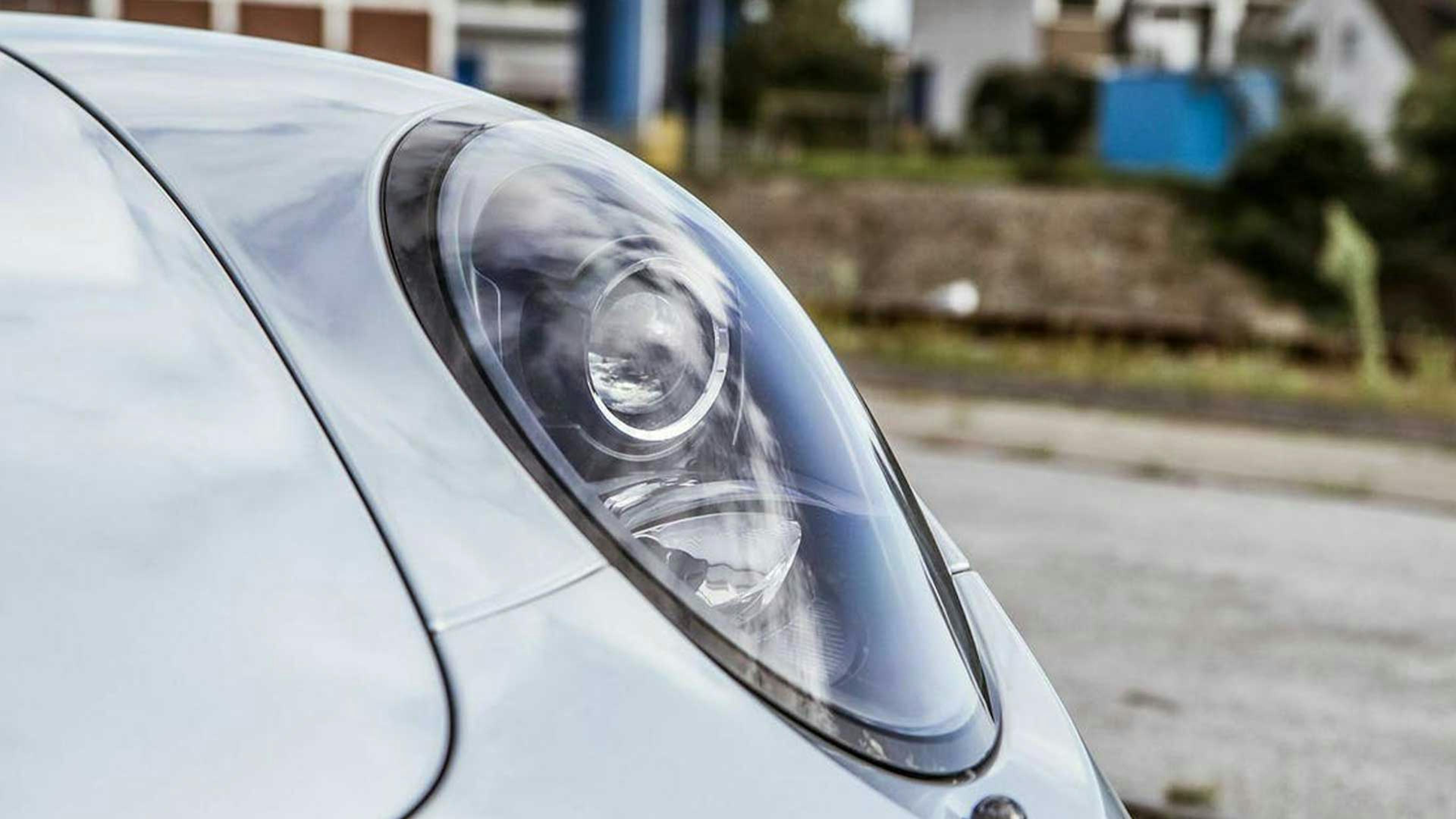 Nahaufnahme eines Frontscheinwerfers an einem silbernen Pkw.