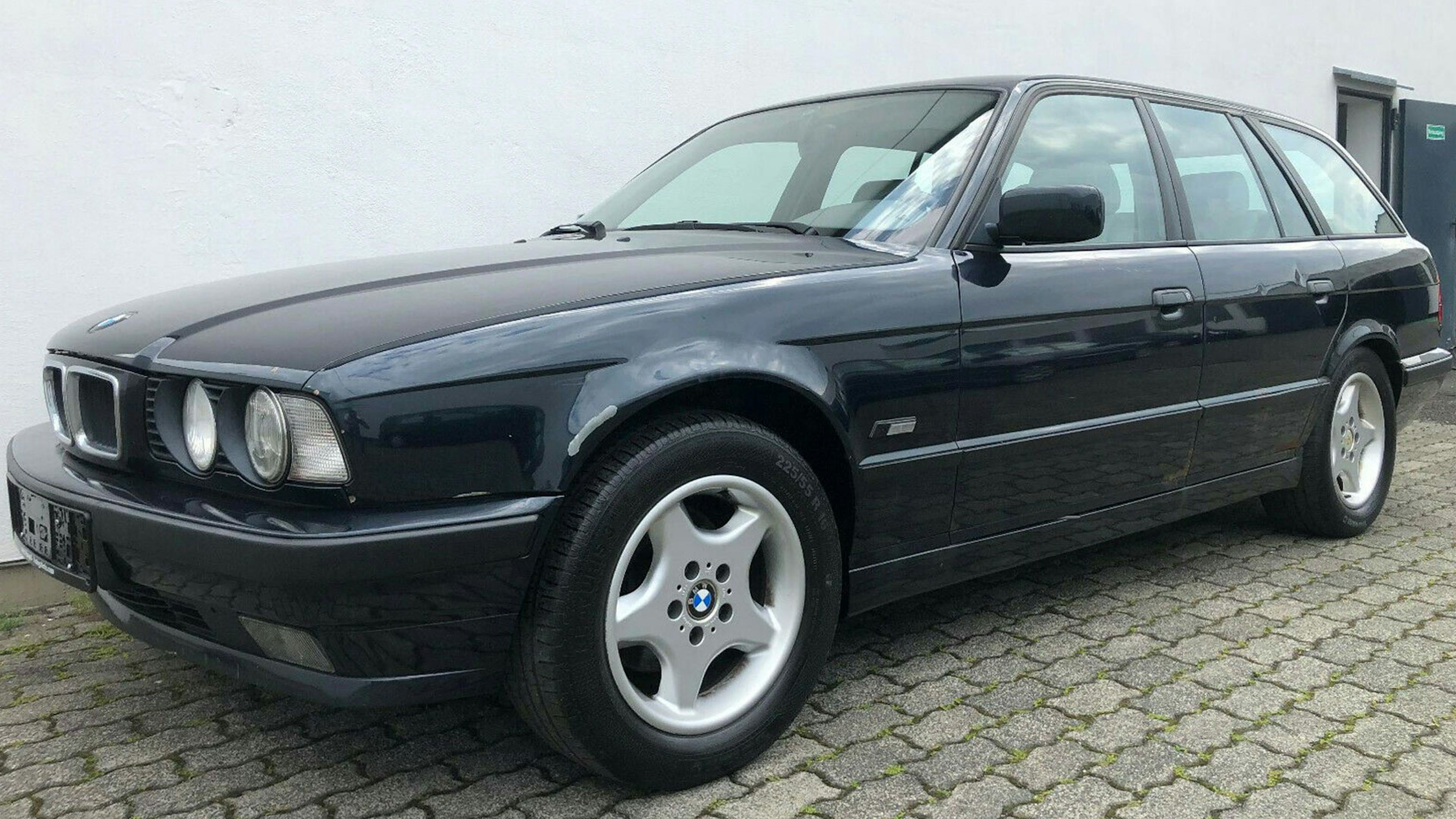 Ein schwarzer BMW 5er Touring steht vor einem weißen Gebäude.