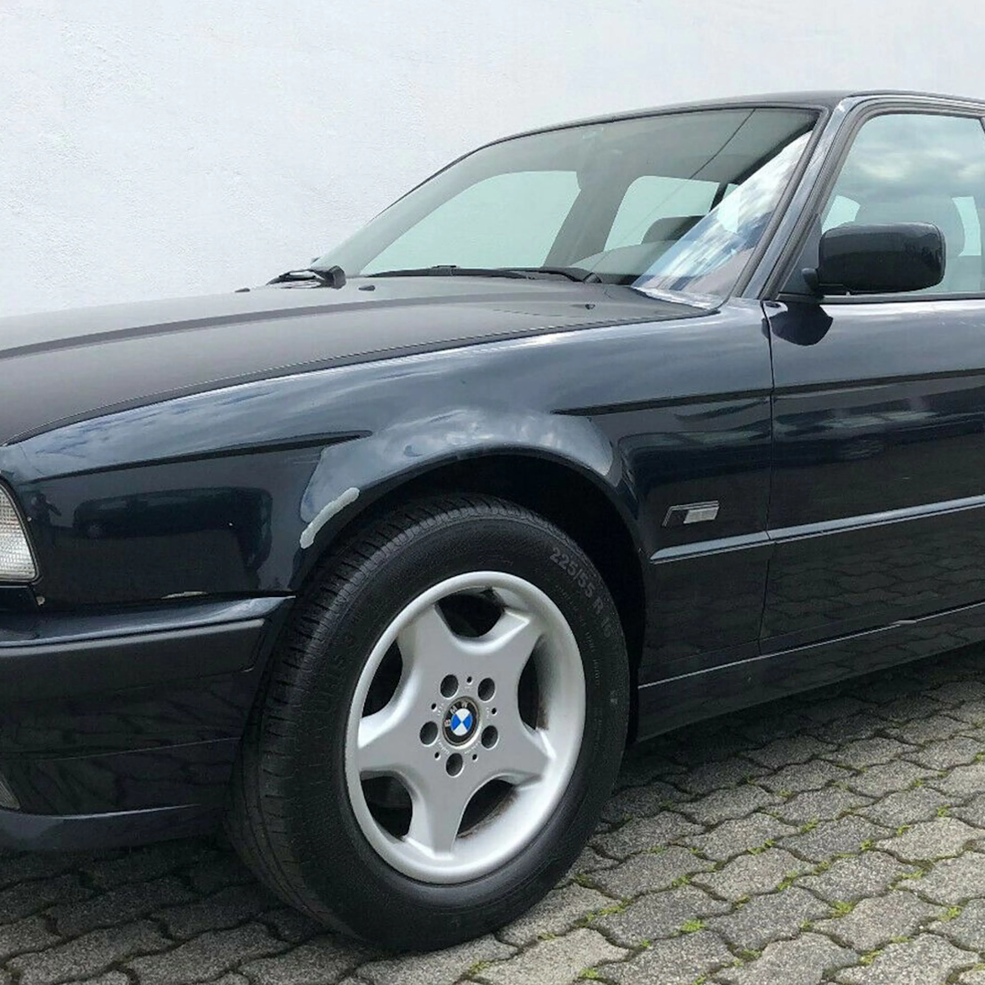 Ein schwarzer BMW 5er Touring steht vor einem weißen Gebäude.