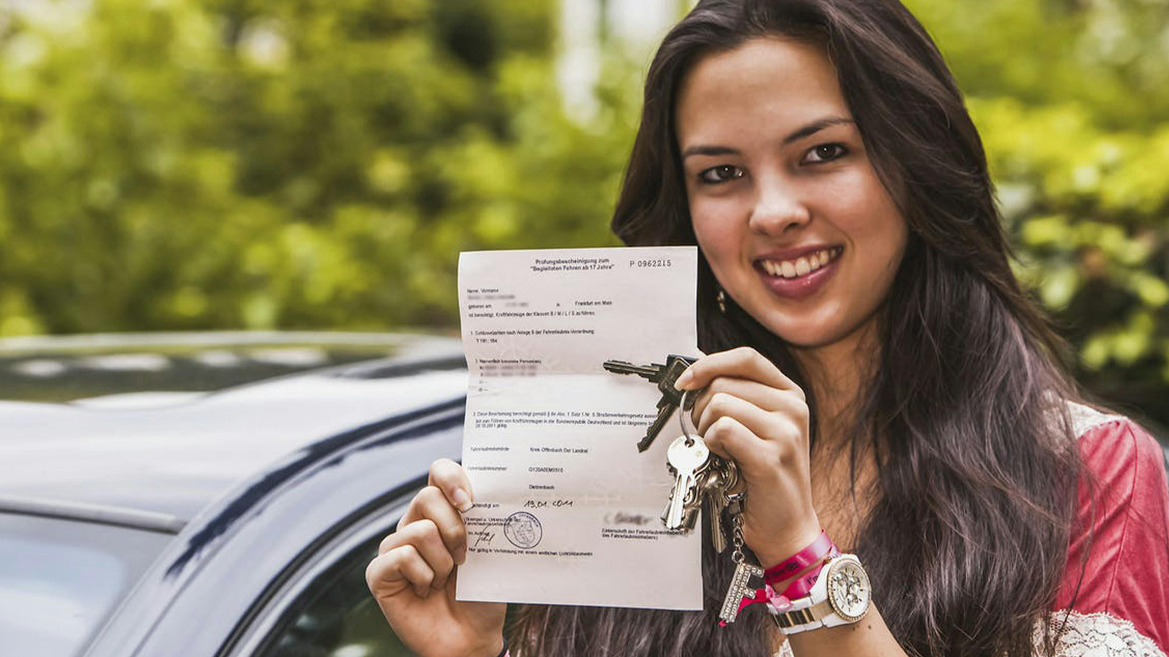 Eine junge Frau zeigt stolz Ihren Führerschein nach bestandener Prüfung