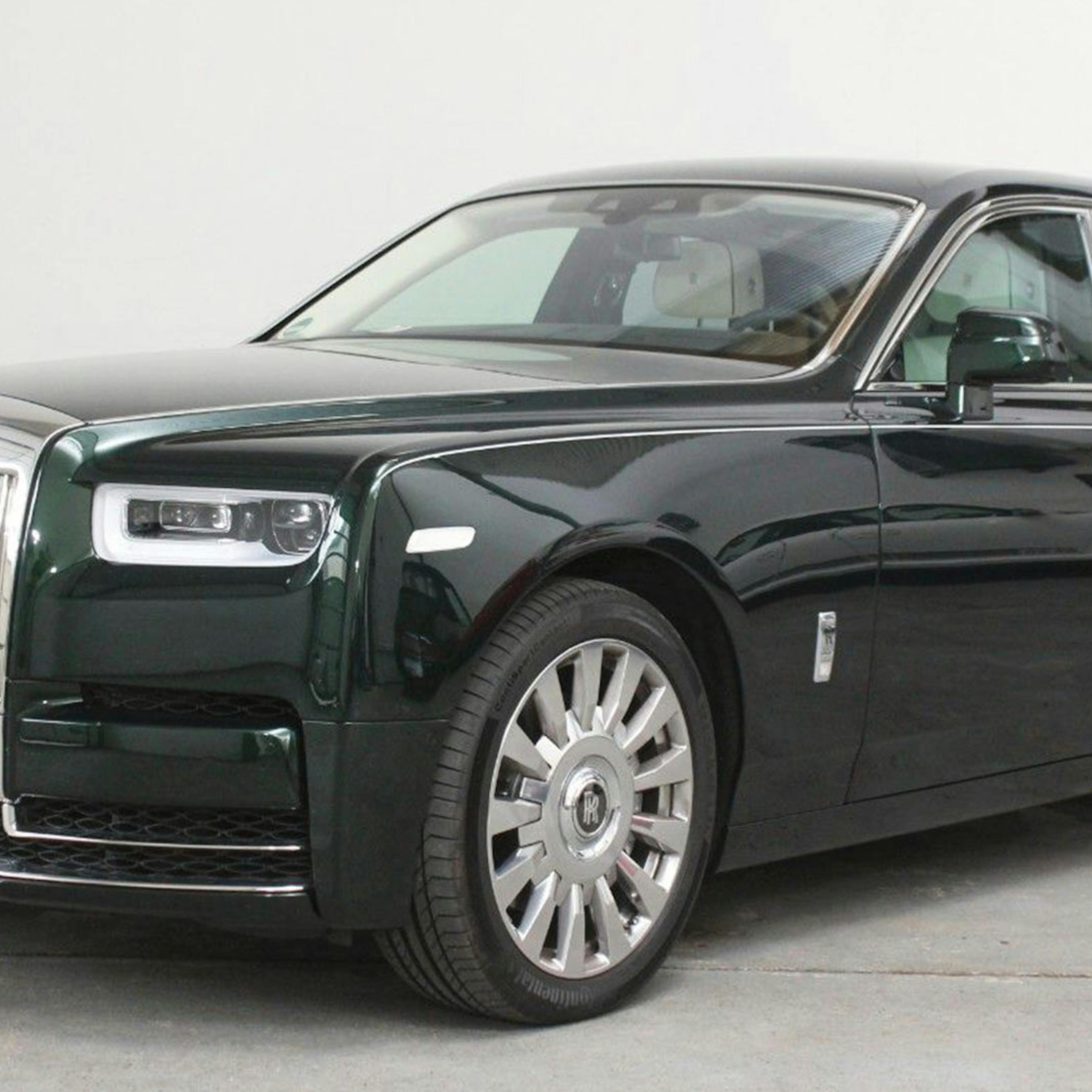 Ein schwarzer Rolls-Royce Phantom steht vor einer weißen Wand.