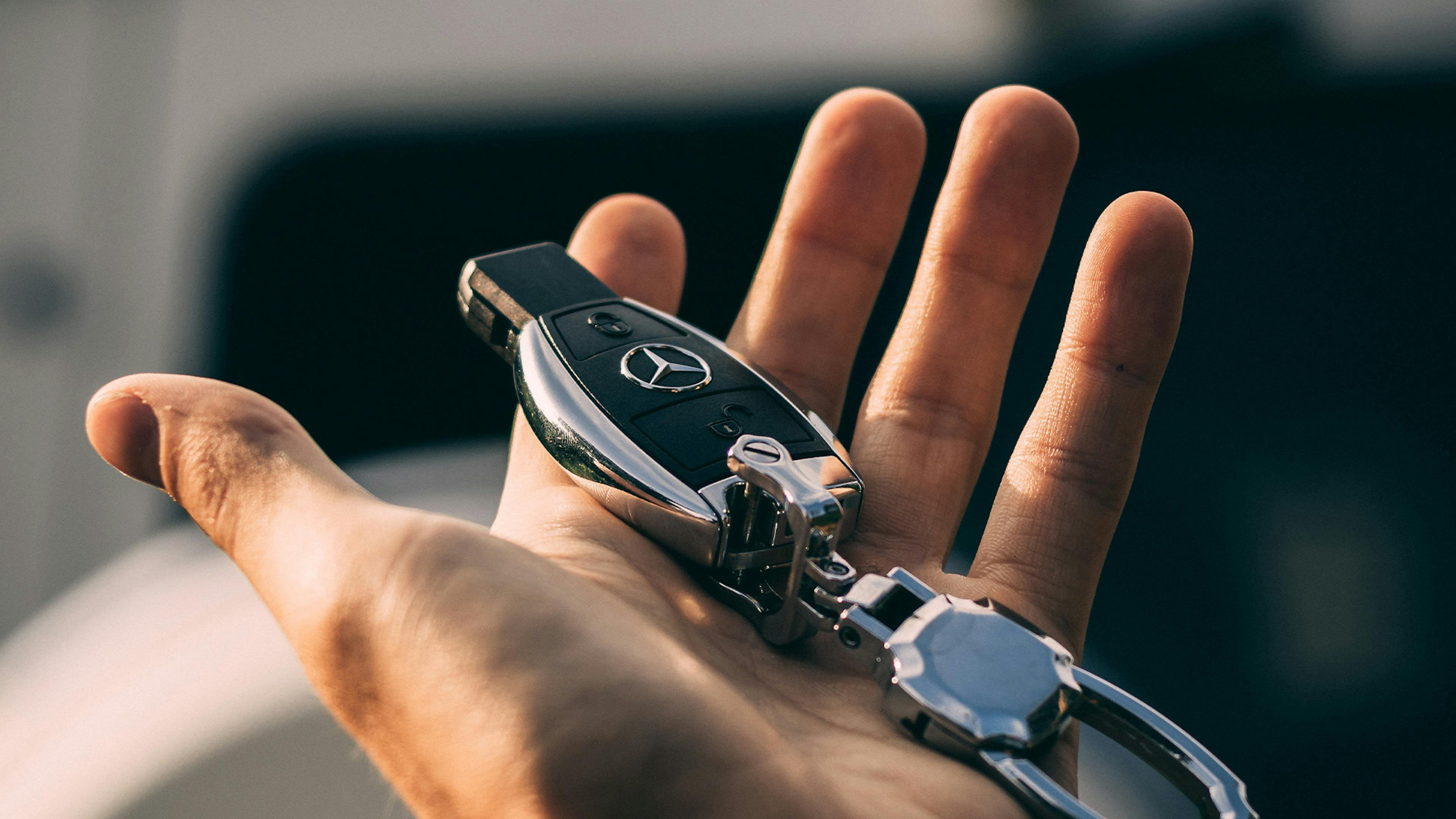 Nahaufnahme einer Hand, die einen Autoschlüssel der Marke Mercedes-Benz hält
