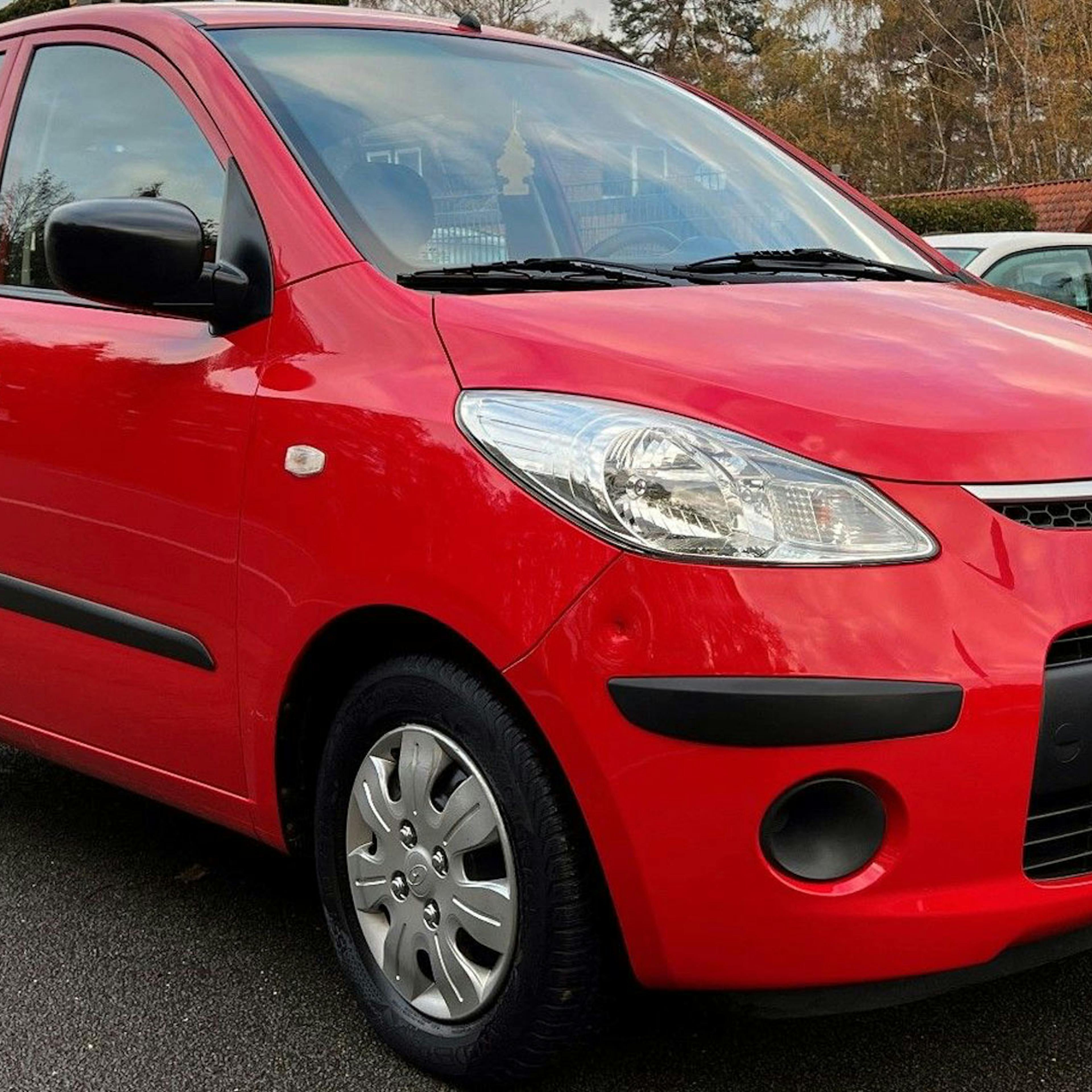 Ein roter Hyundai i10 Kleinstwagen steht auf einem Parkplatz.