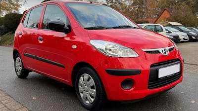 Ein roter Hyundai i10 Kleinstwagen steht auf einem Parkplatz.