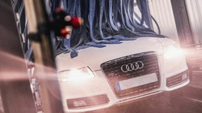Ein weißer Audi wird in einer Waschanlage gereinigt.