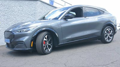 Ein graues Ford-Mustang-Mach-E-Elektroauto mit Allradantrieb steht in einer Einfahrt.