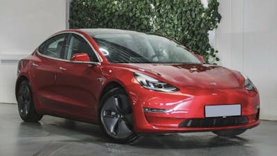 Ein rotes Tesla Model 3 Elektroauto mit Allradantrieb steht in einem Autohaus.