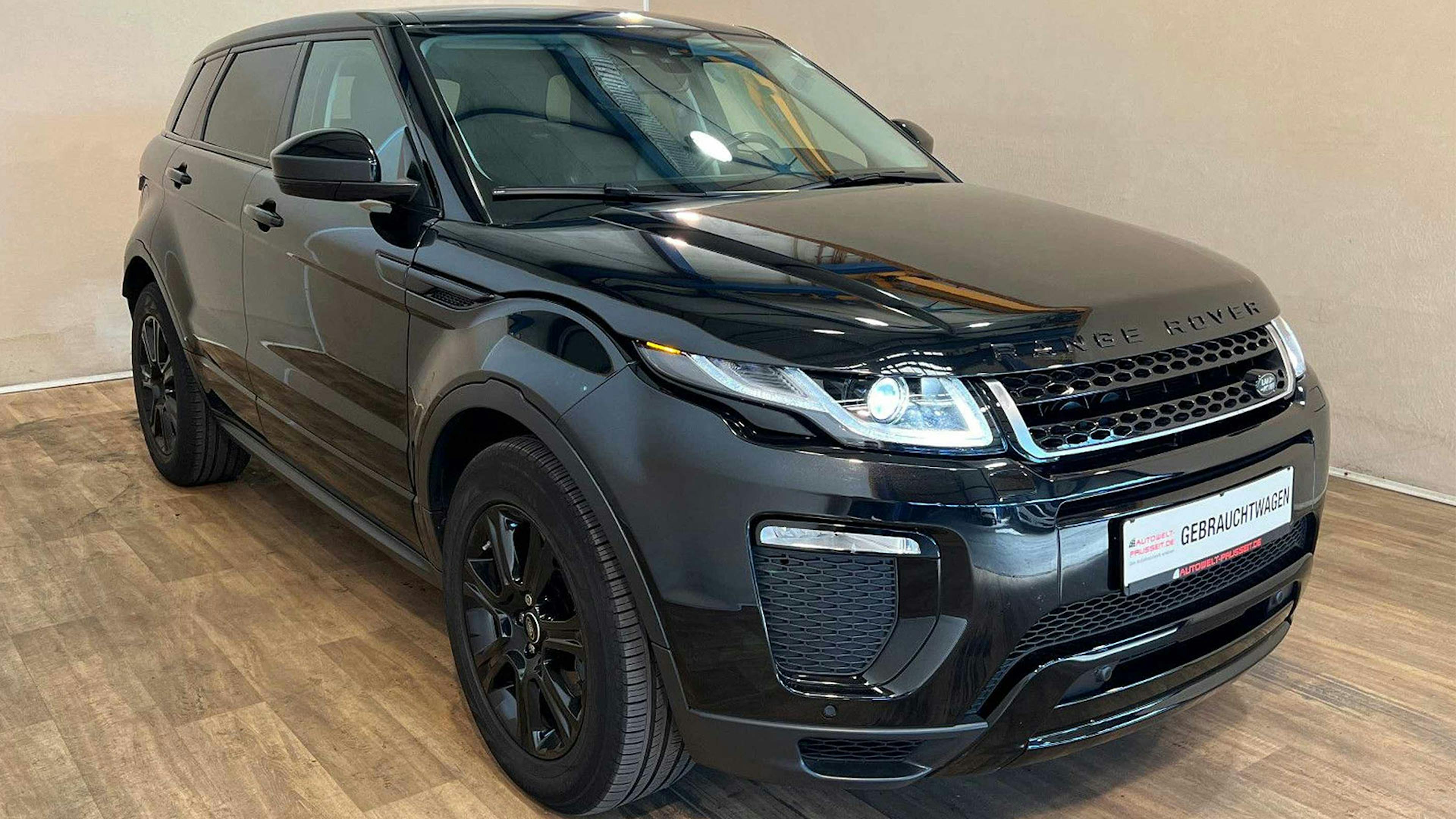 Ein schwarzer Range Rover Evoque Geländewagen steht in einem hellen Raum.