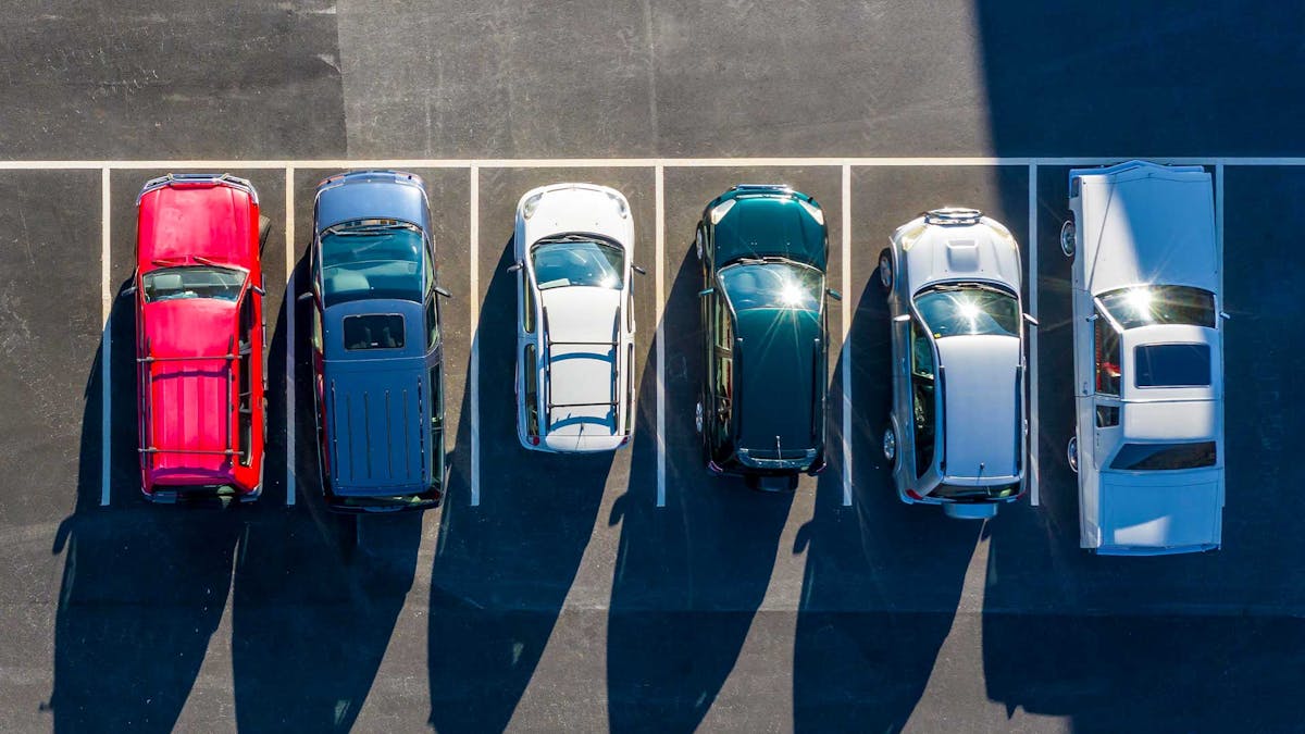 Luftaufnahme von sechs Pkw verschiedener Fahrzeugklassen, die auf einem Parkplatz stehen
