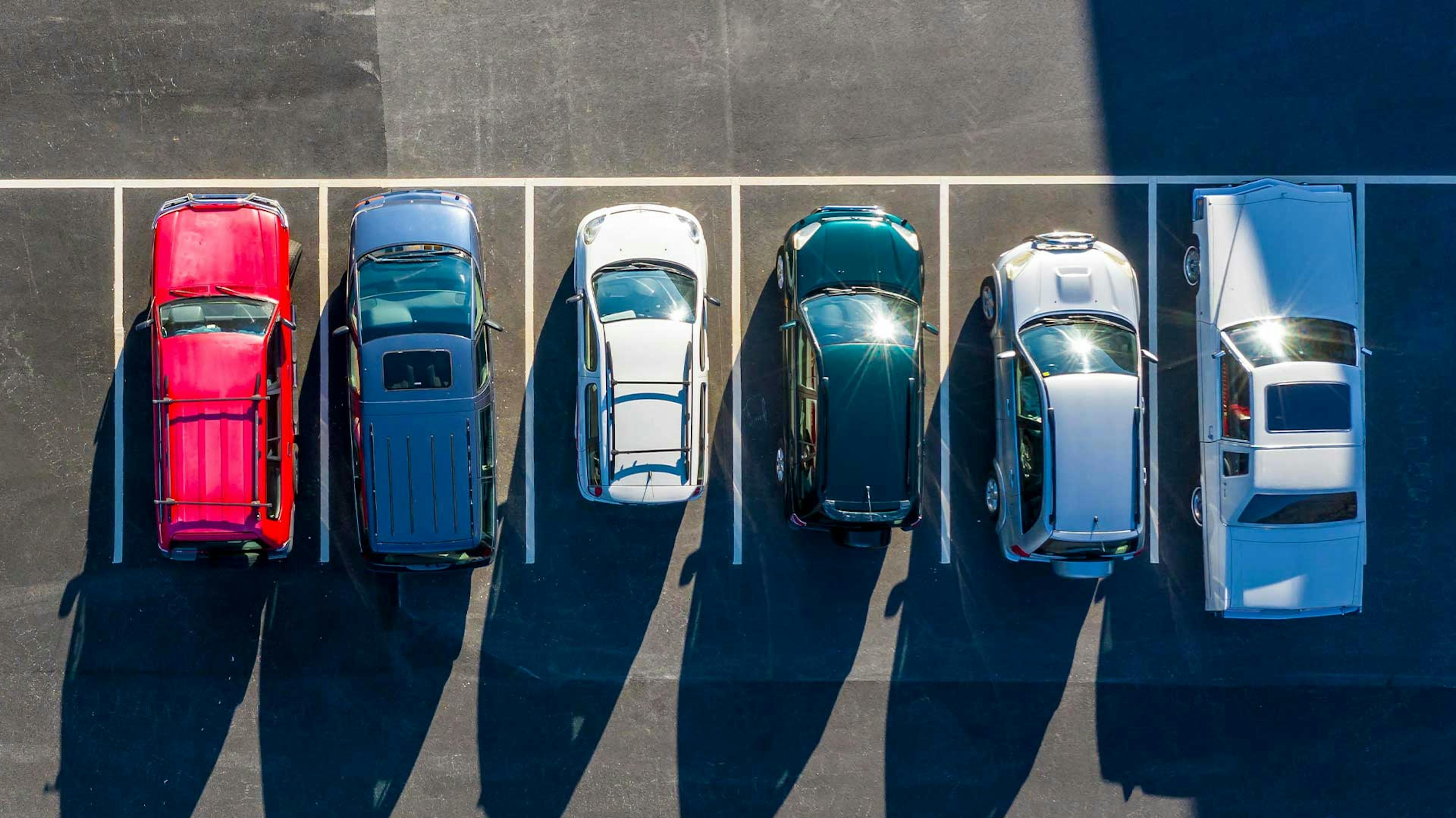 Luftaufnahme von sechs Pkw verschiedener Fahrzeugklassen, die auf einem Parkplatz stehen