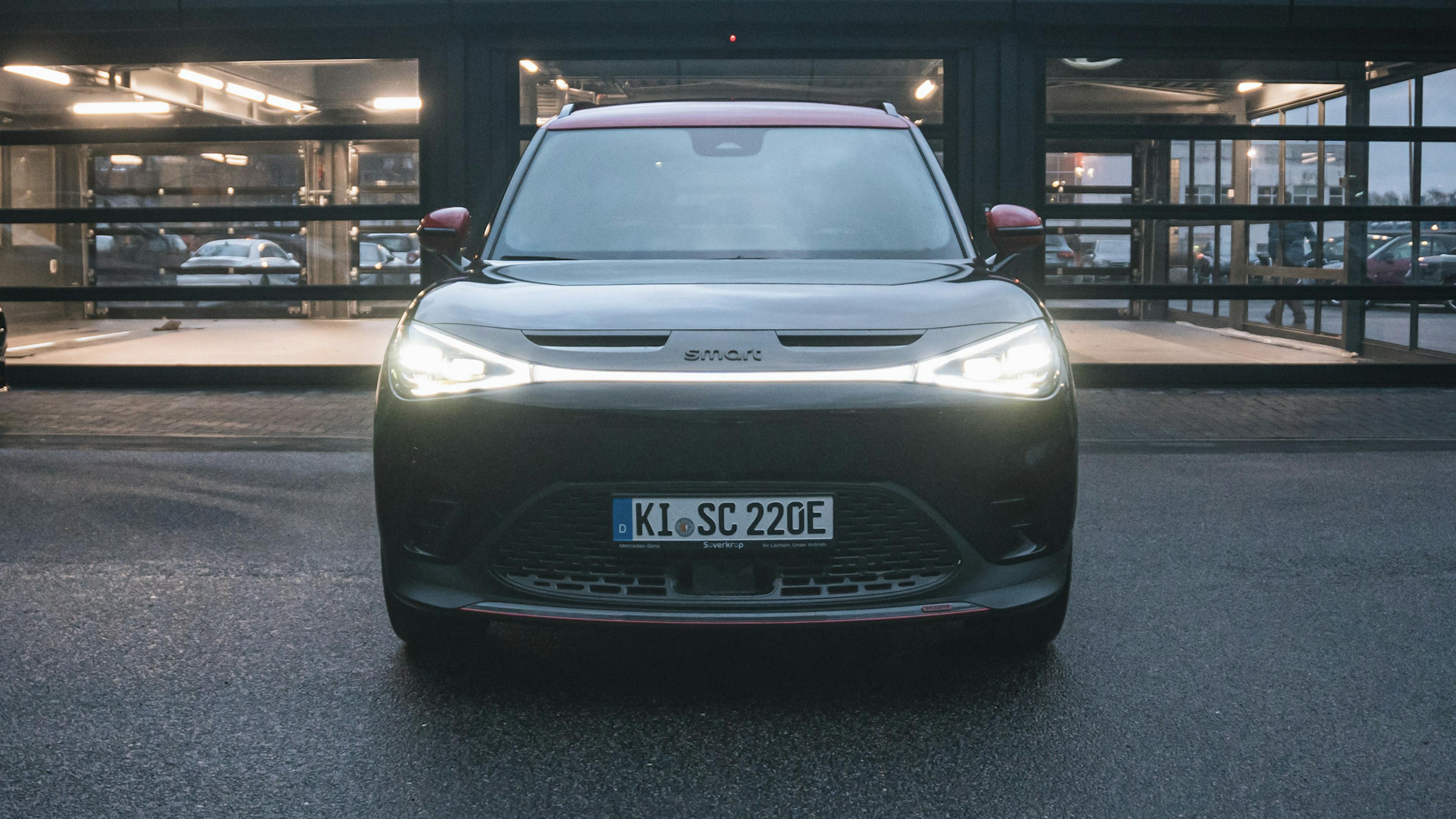 Eine schwarz-roter Brabus #1 steht vor einer beleuchteten Halle.