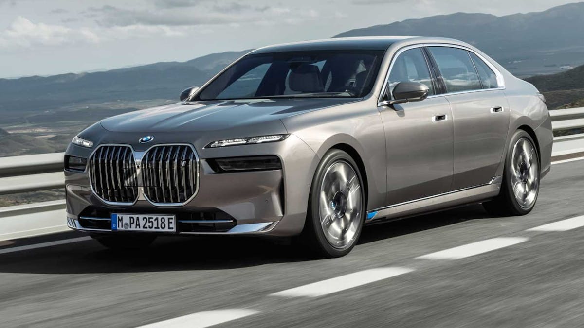 Ein silbernes BMW i7 Elektroauto fährt eine Landstraße entlang.