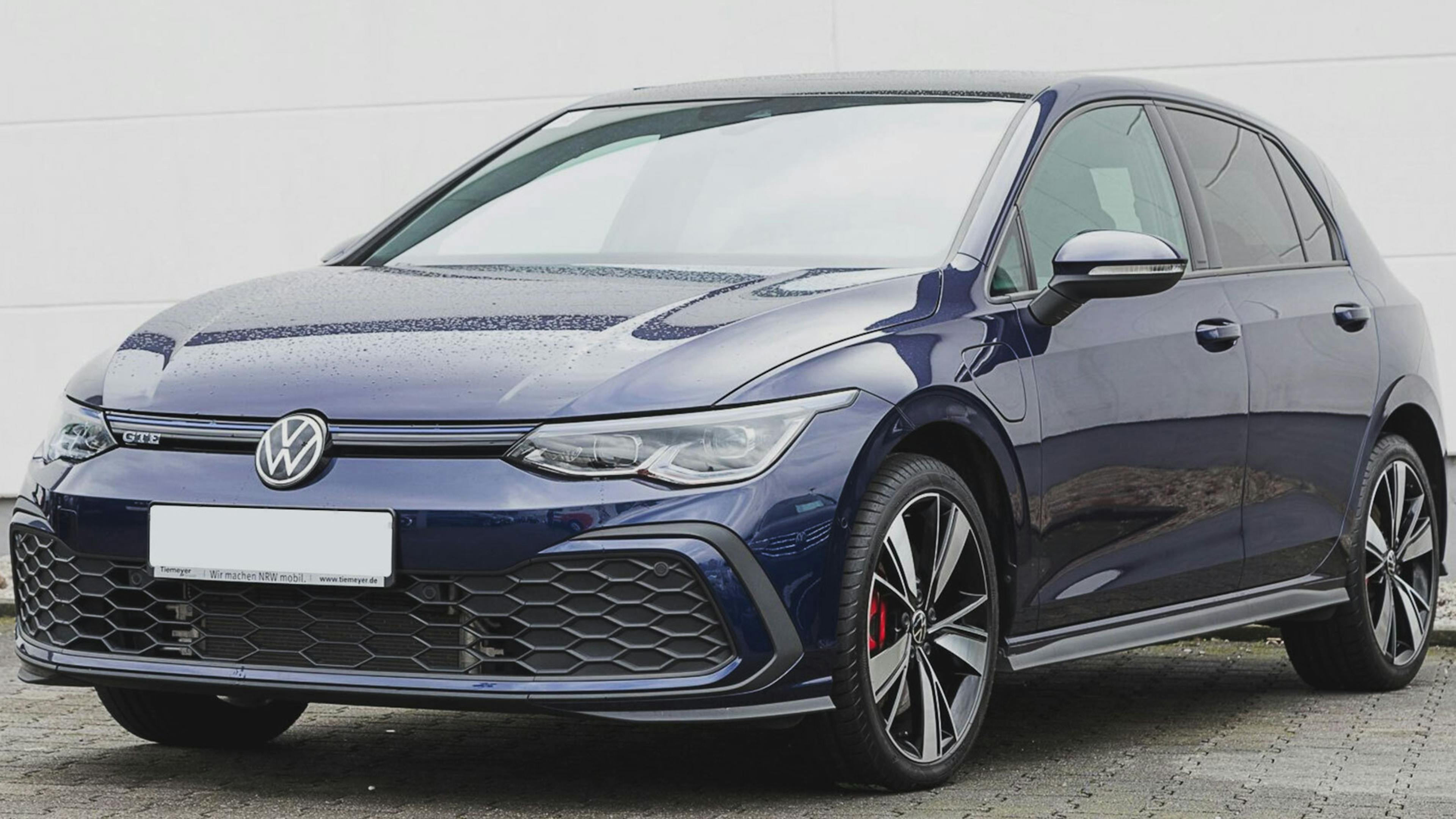 Ein blauer VW Golf GTE Plug-in-Hybrid steht vor einer weißen Wand