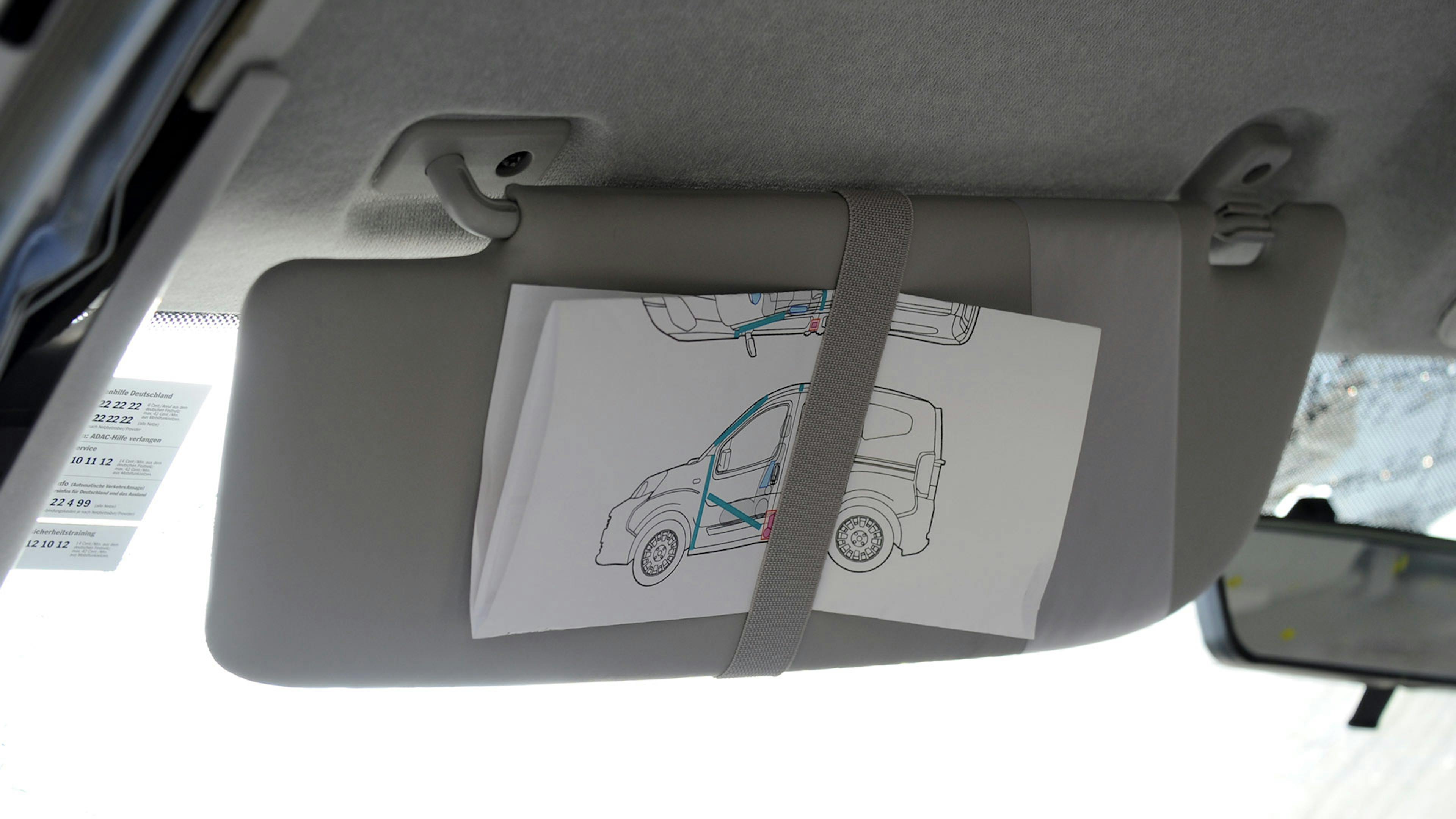 Eine Rettungskarte ist mit einer Schlaufe hinter die Sonnenblende auf der Fahrerseite geklemmt.