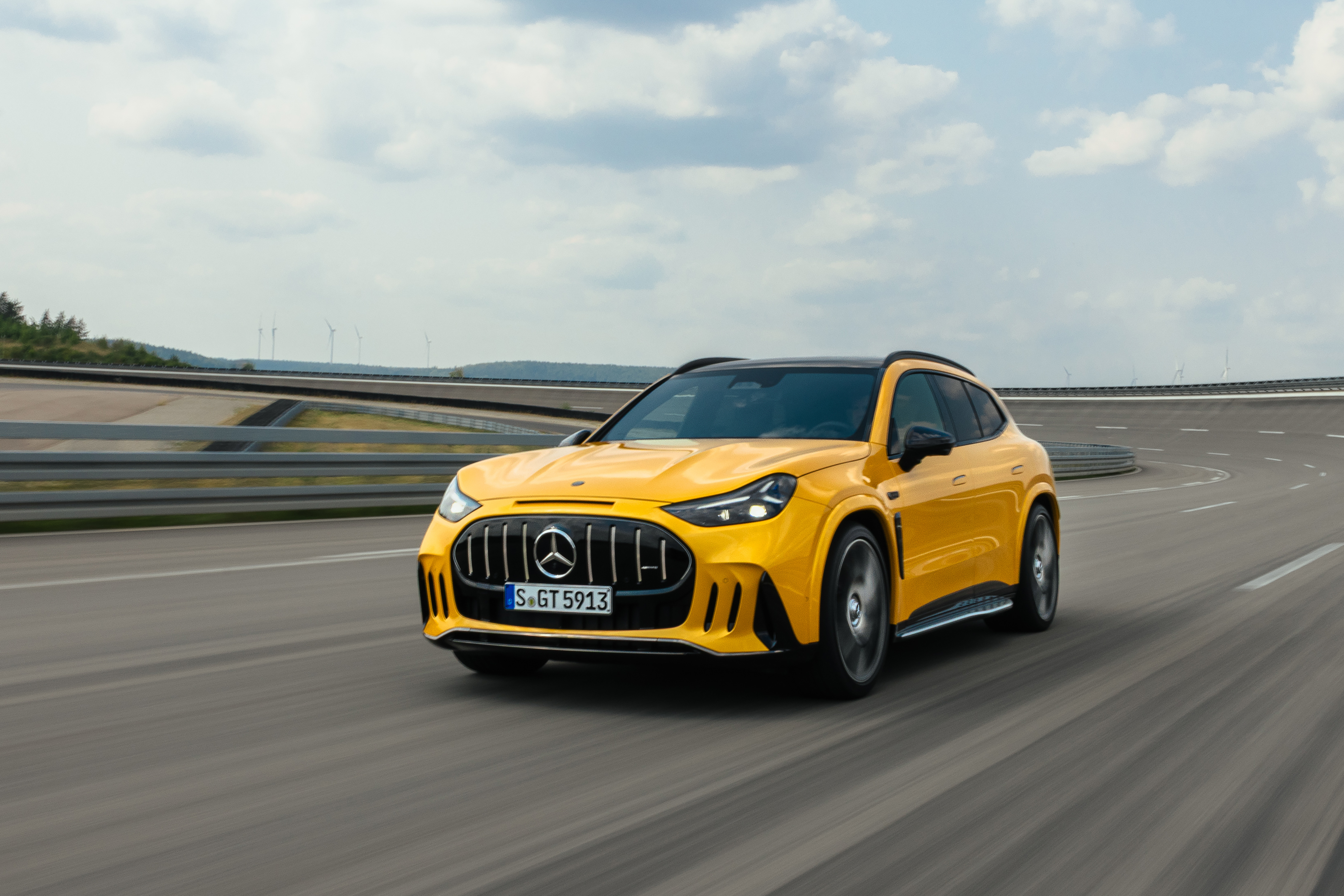 Gelber Mercedes-AMG GT SUV fährt auf einer Rennstrecke, Blick auf die Front mit dem Lamellengrill