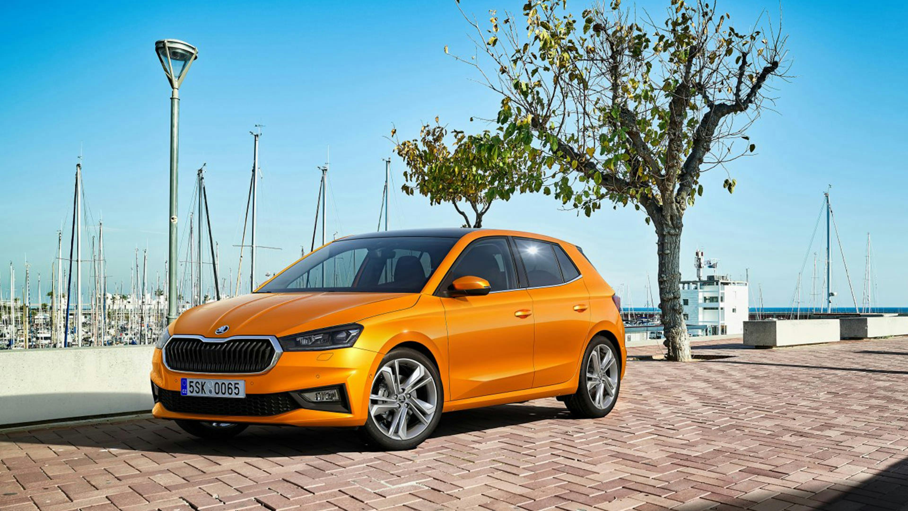 Ein orangefarbener Škoda Fabia parkt an einem Hafen.