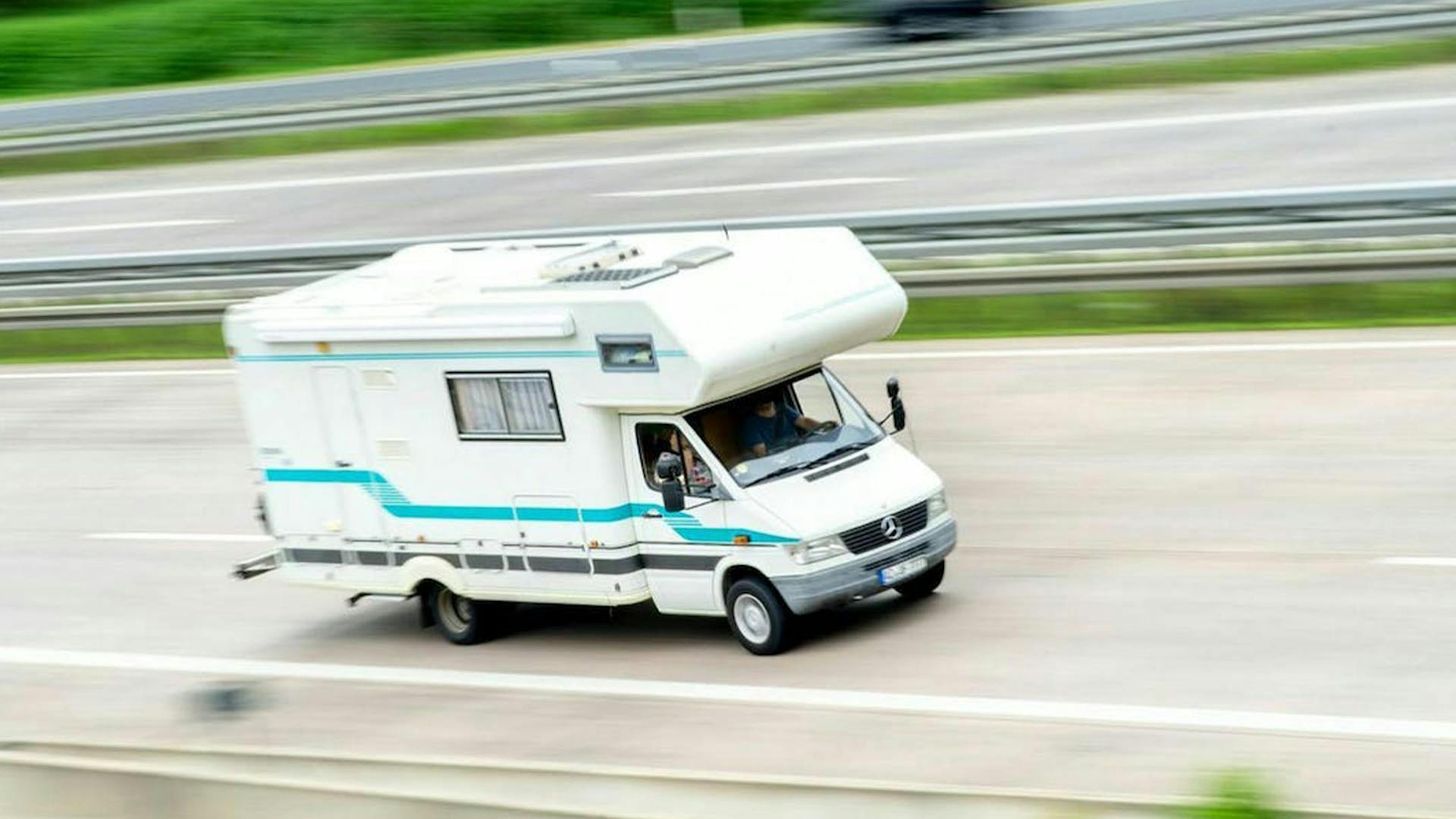 Ein weißes Wohnmobil fährt auf einer Autobahn.