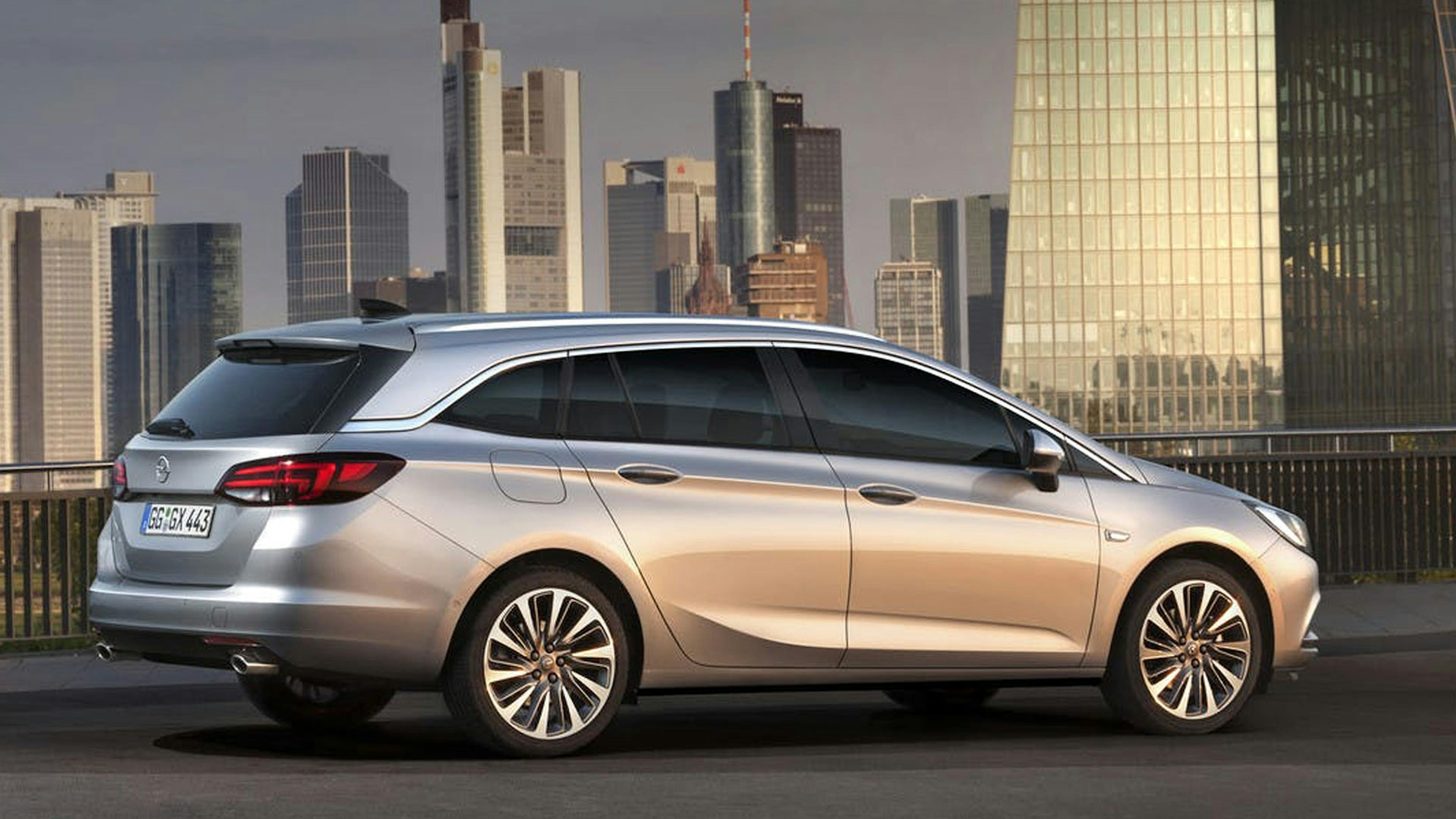 Ein silberner Opel Astra K Sports Tourer steht vor einer urbanen Kulisse.