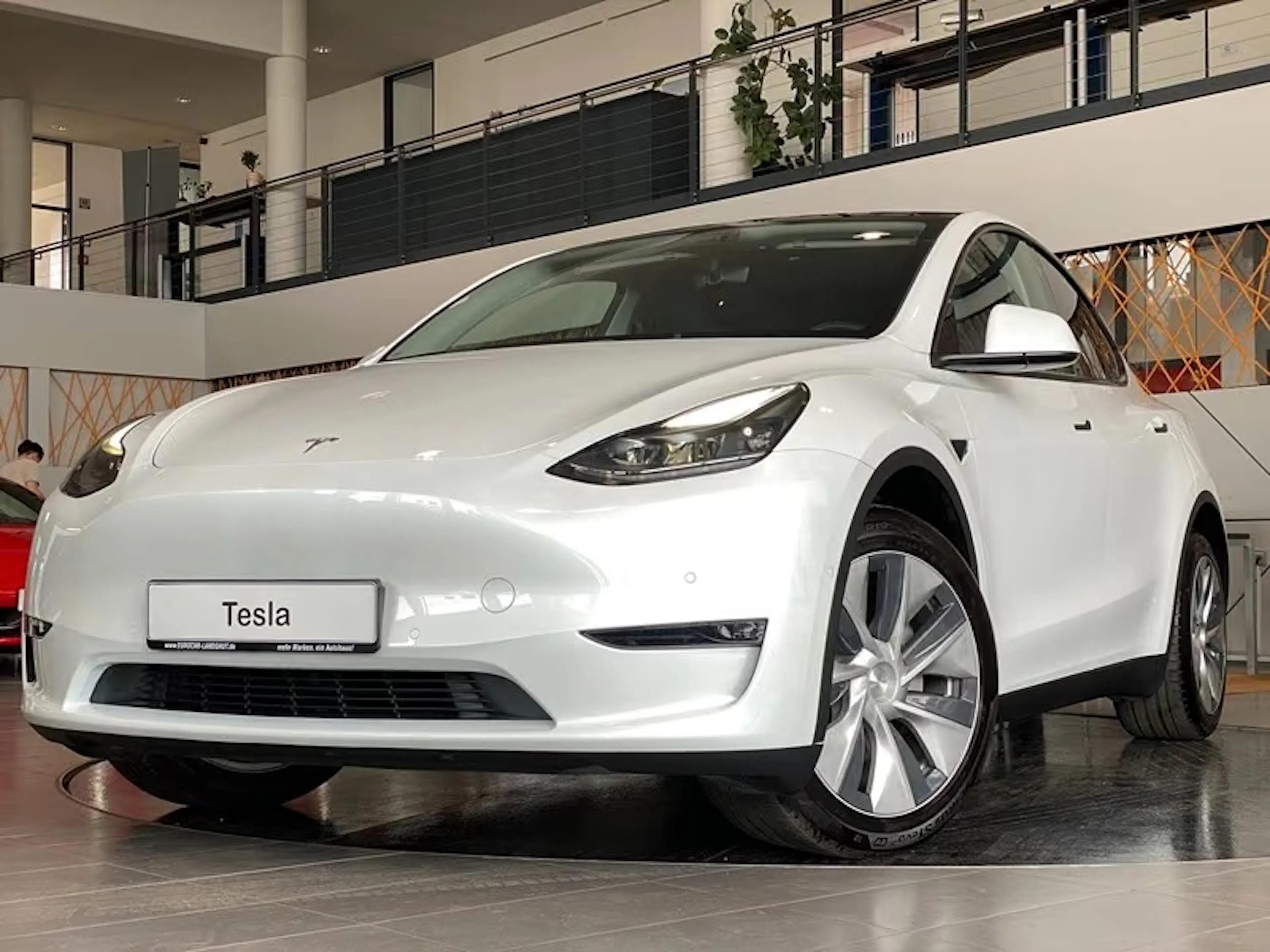 Ein weißes Tesla Model Y AWD Long Range steht in einer Verkaufshalle.