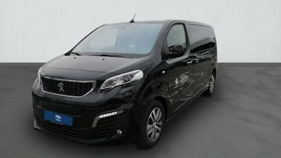 Ein schwarzer Peugeot e-Traveller steht vor einer weißen Wand.