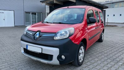 Ein roter Renault Kangoo Z.E. Elektrotransporter steht auf einem leeren Parkplatz hinter einer Halle