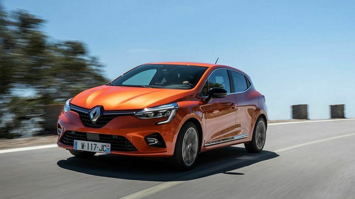 Ein orange-roter Renault Clio fährt eine Küstenstraße entlang.