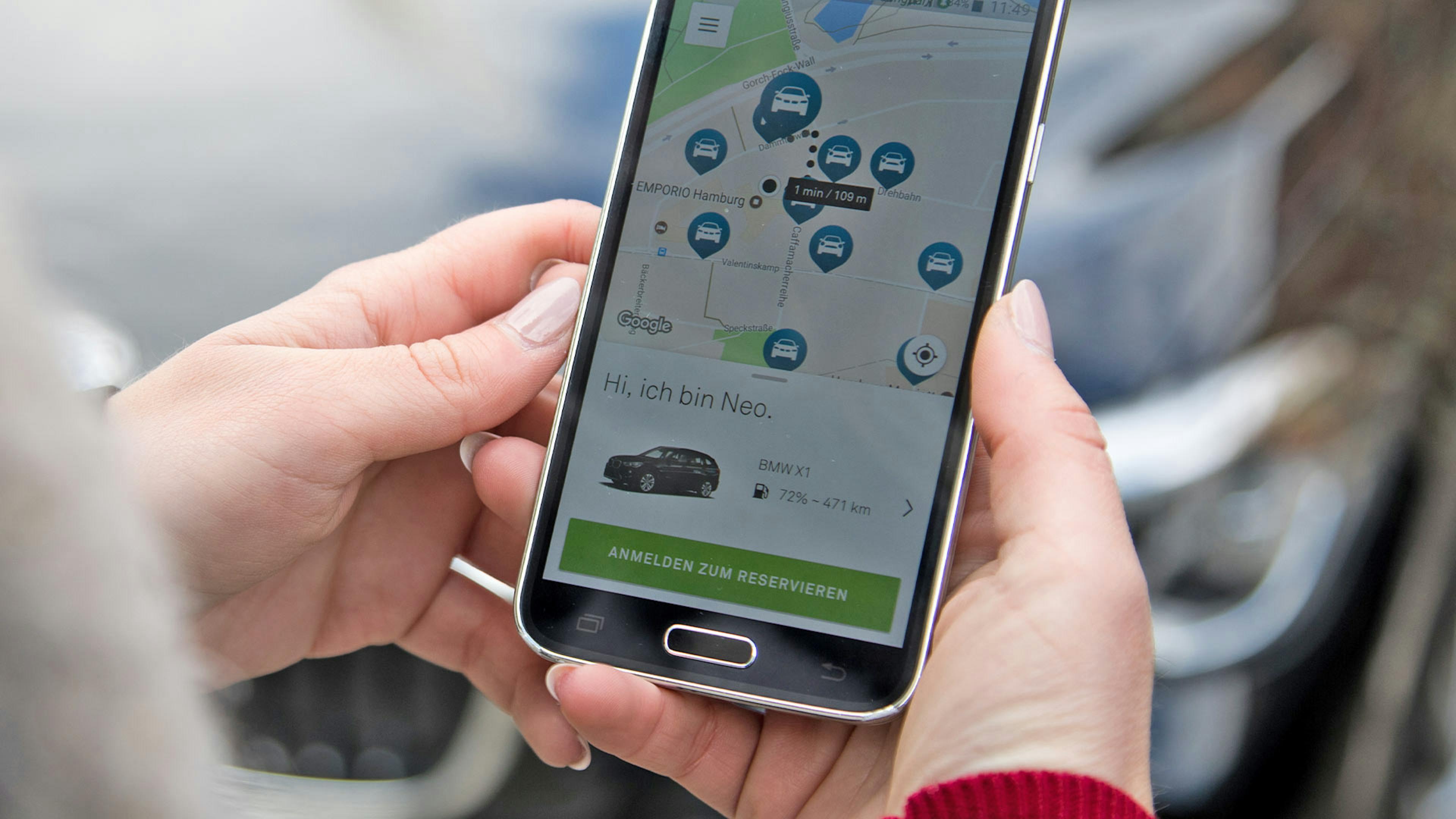 Eine Frau sucht einen Pkw über eine Carsharing-App.