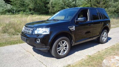 Ein schwarzer Land Rover Freelander Geländewagen steht vor einer Wiese.