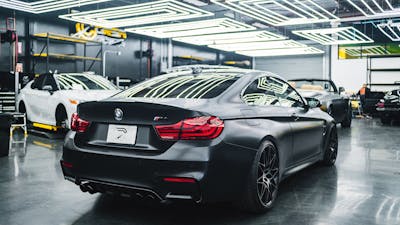 Blick in ein Autohaus mit einem schwarzen BMW im Vordergrund.