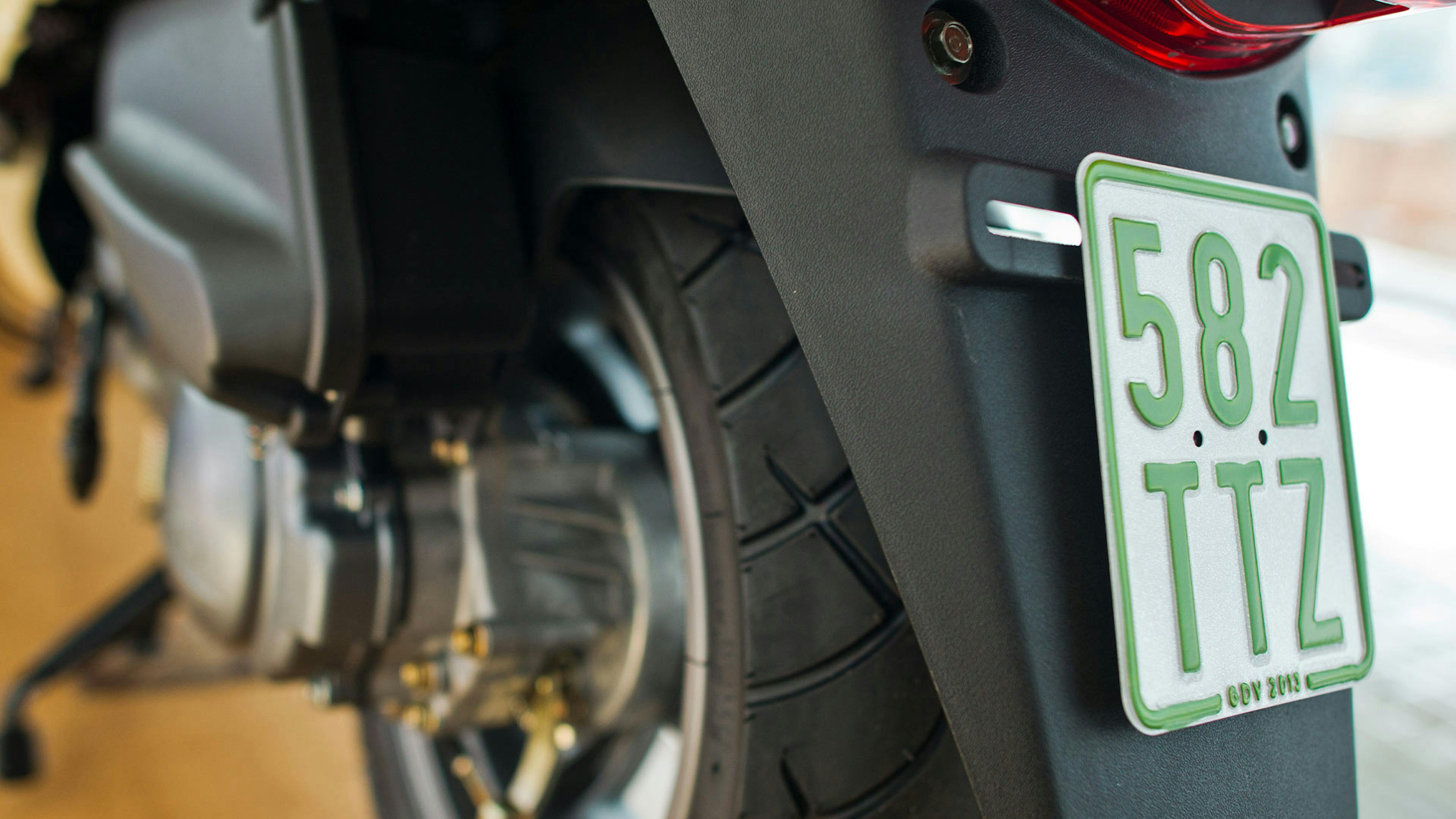 Nahaufnahme eines grünen Versicherungskennzeichens an einem Motorrad.