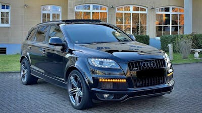 Ein schwarzer Audi Q7 4.2 TDI V8 steht vor einem gelben Gebäude.