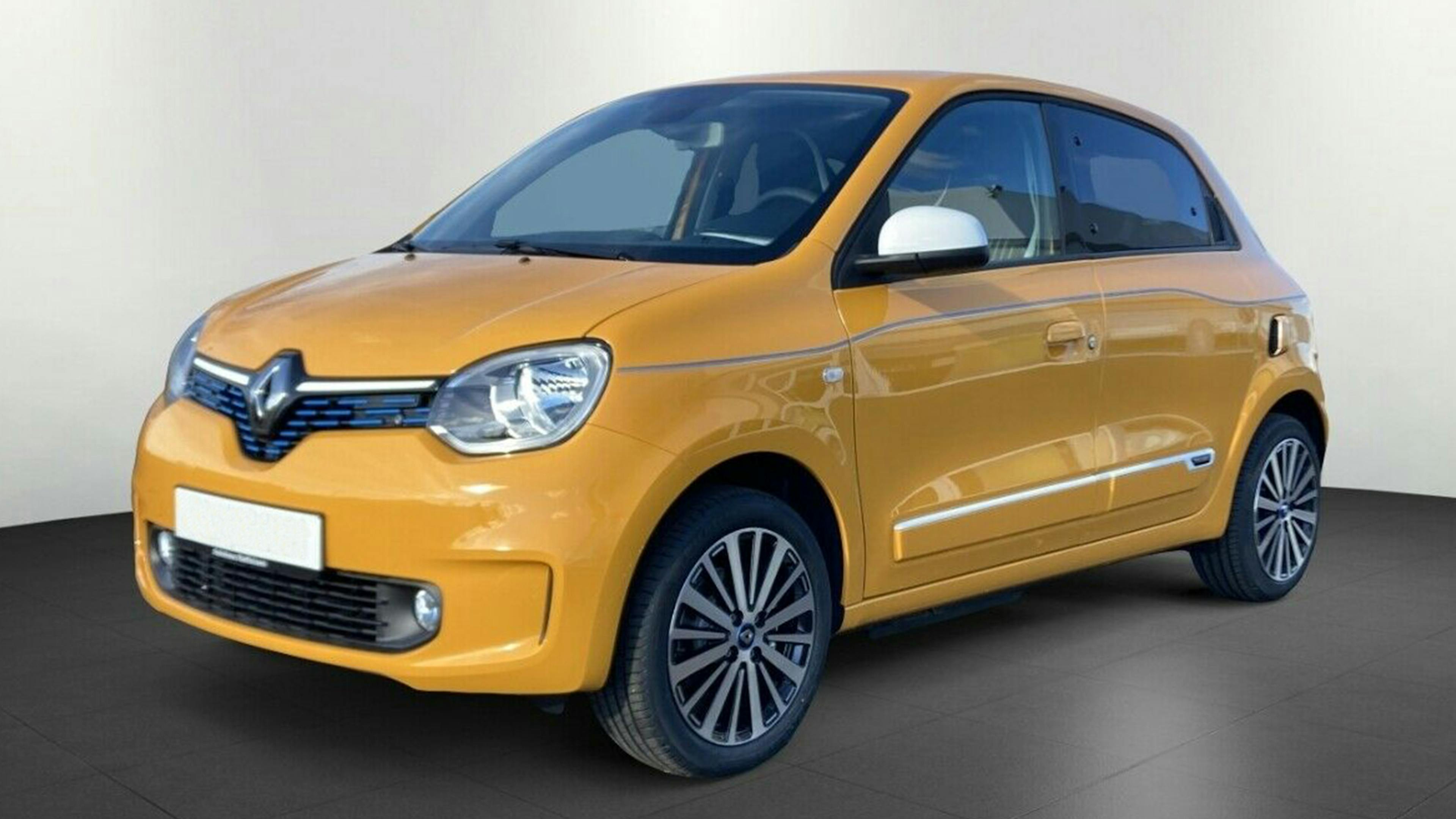 Ein goldener Renault Twingo Electric steht vor einer weißen Wand.