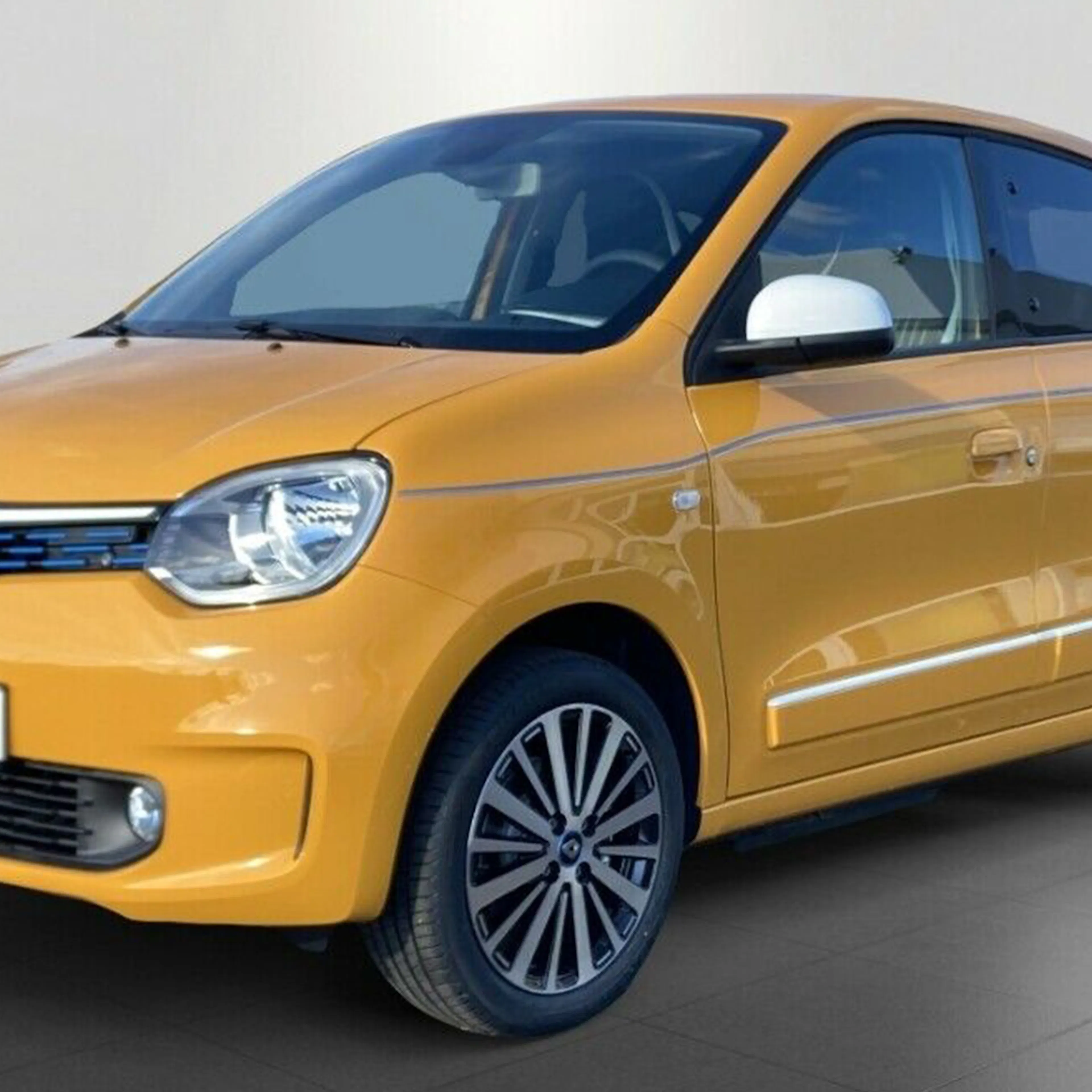 Gelber Renault Twingo Kleinwagen, schräg von vorn fotografiert. Weißes Außenspiegelgehäuse und schwarze Felgen mit silbernen Akzenten.