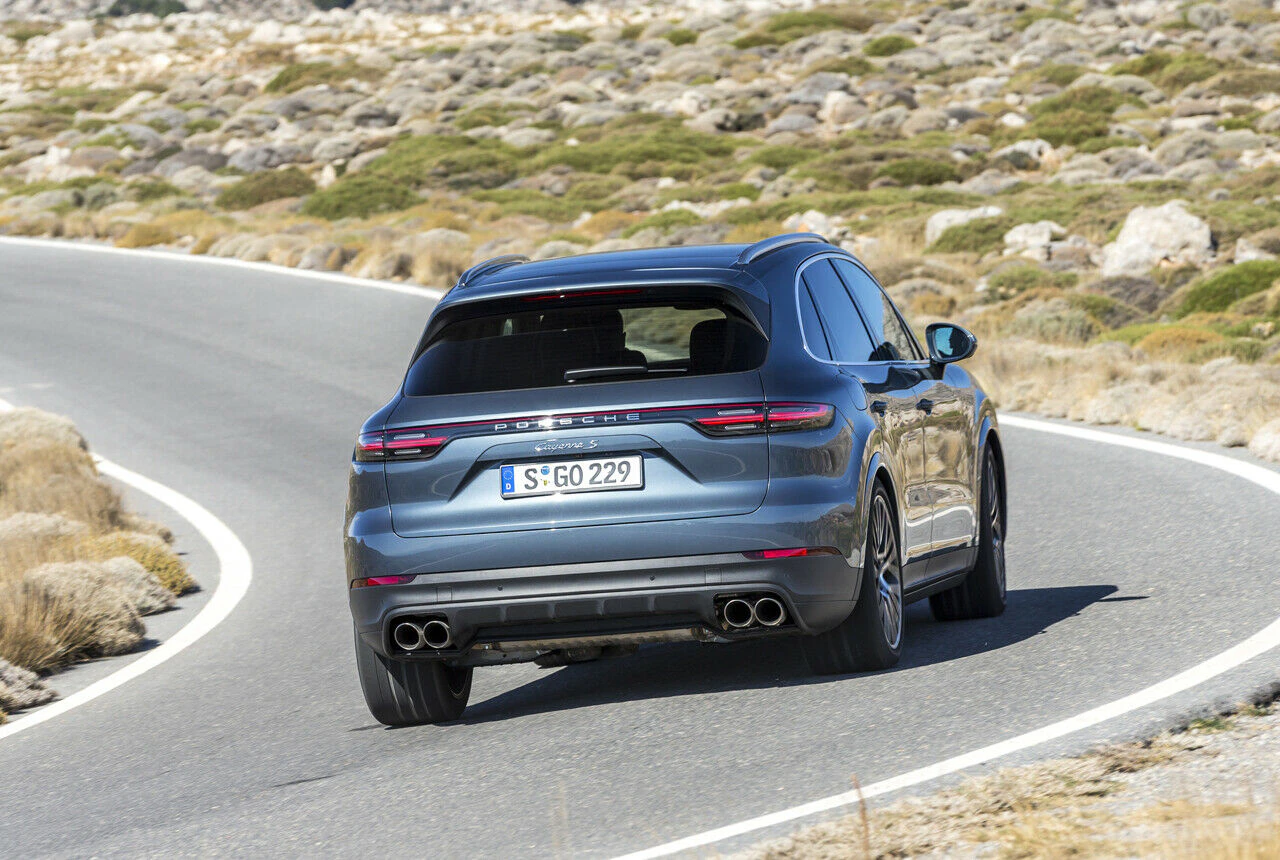 Ein grauer Sportwagen fährt auf einer kurvigen Straße durch eine trockene Landschaft.