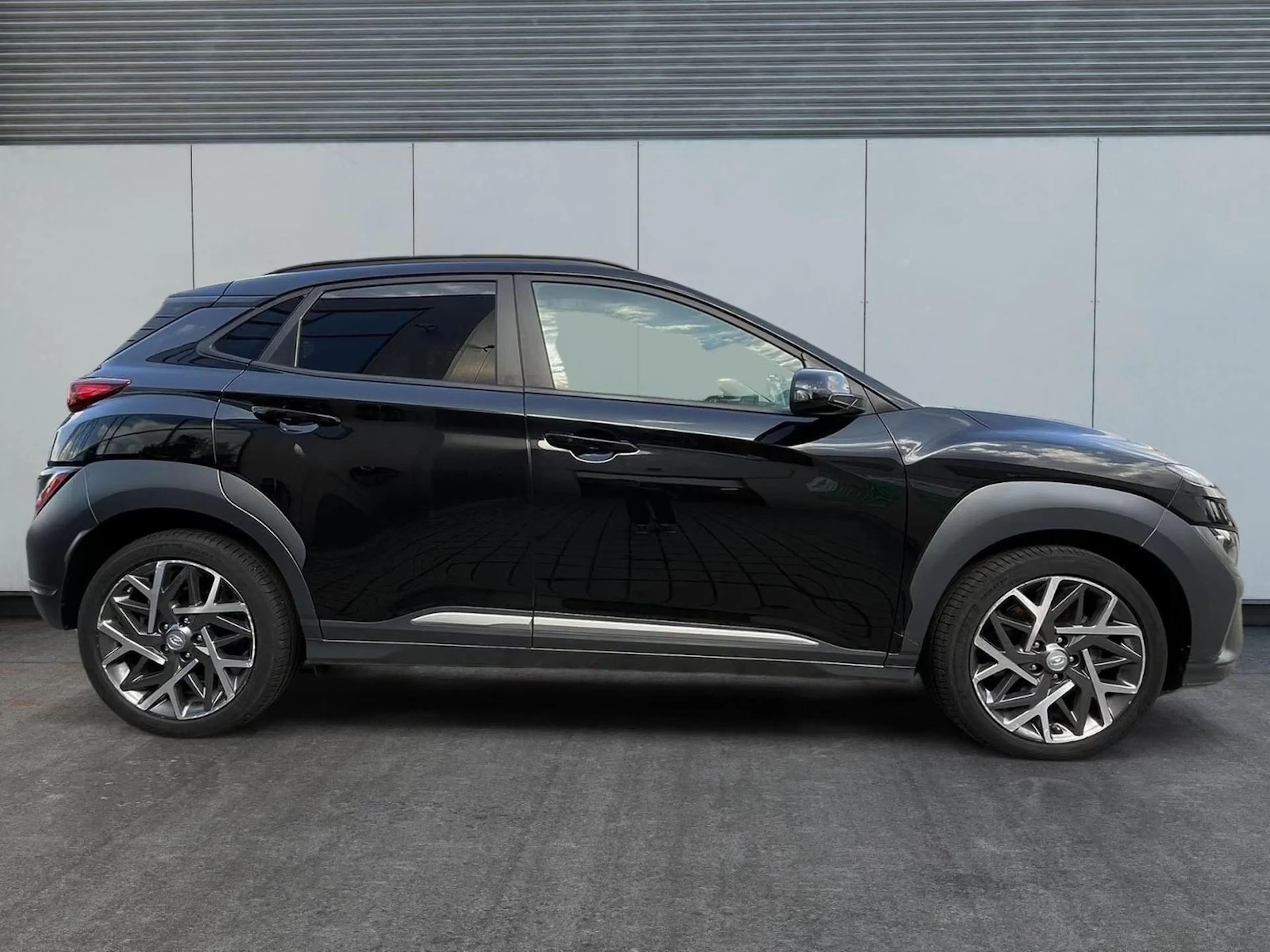 Ein dunkel lackierter Hyundai Kona steht auf einer gepflasterten Fläche.