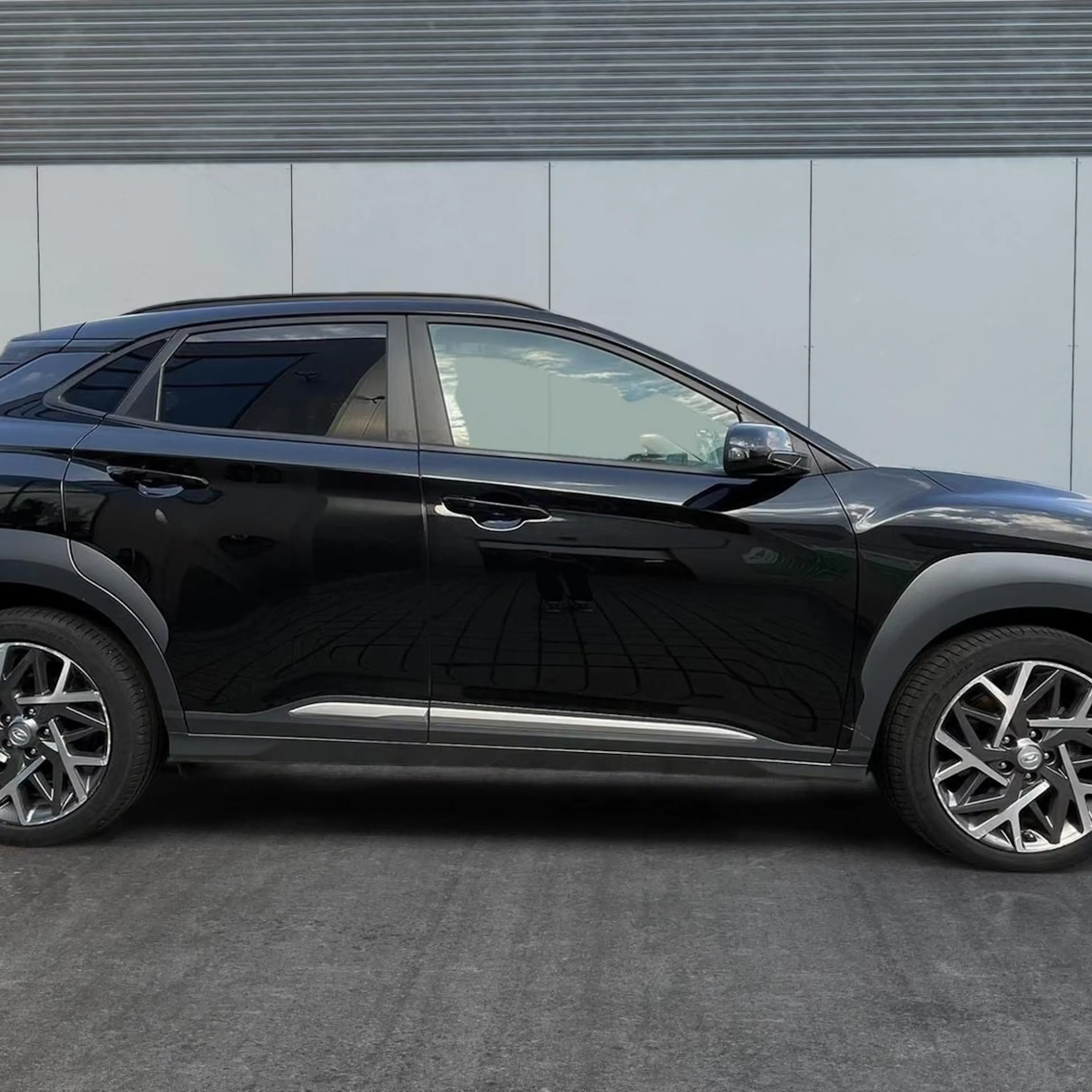 Ein dunkel lackierter Hyundai Kona steht auf einer gepflasterten Fläche.