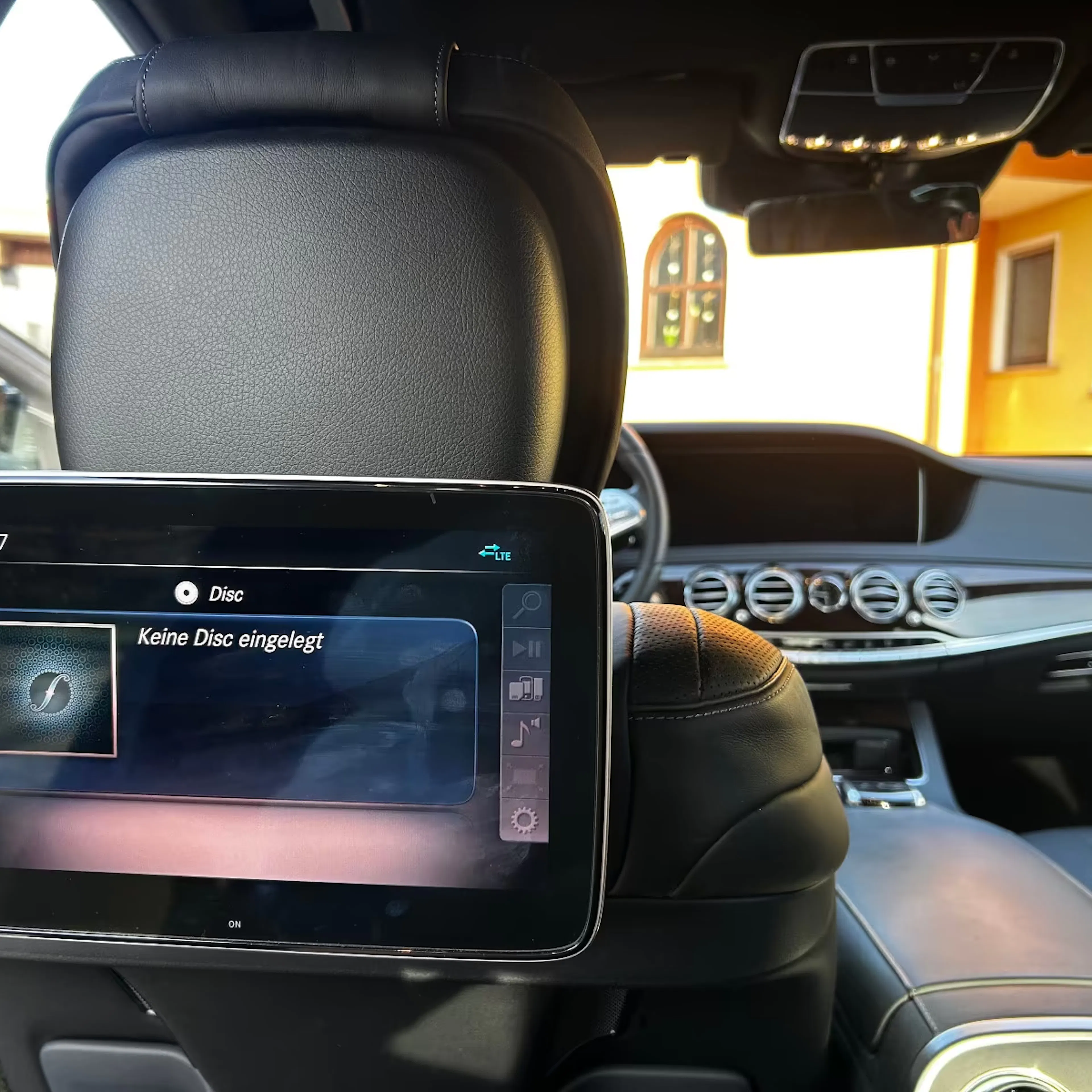 Blick in den Innenraum des Mercedes-Benz. Es ist ein Display zu sehen, das an der Rückseite des Fahrersitzes angebracht ist.