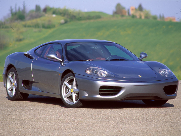Ein silberner Ferrari 360 Modena steht vor einem grünen Hügel.