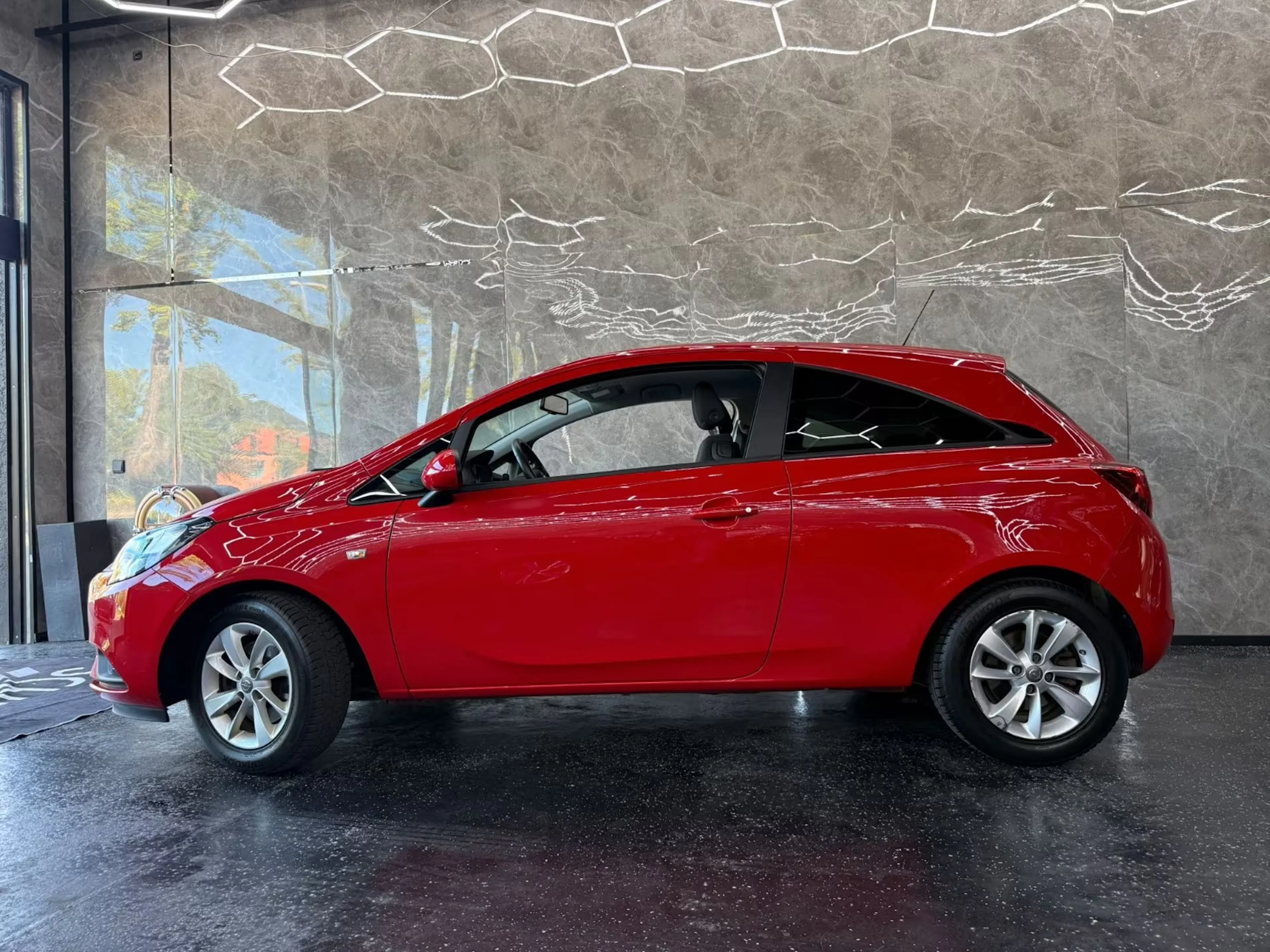 Ein roter Opel Corsa steht auf einer Verkaufsfläche.