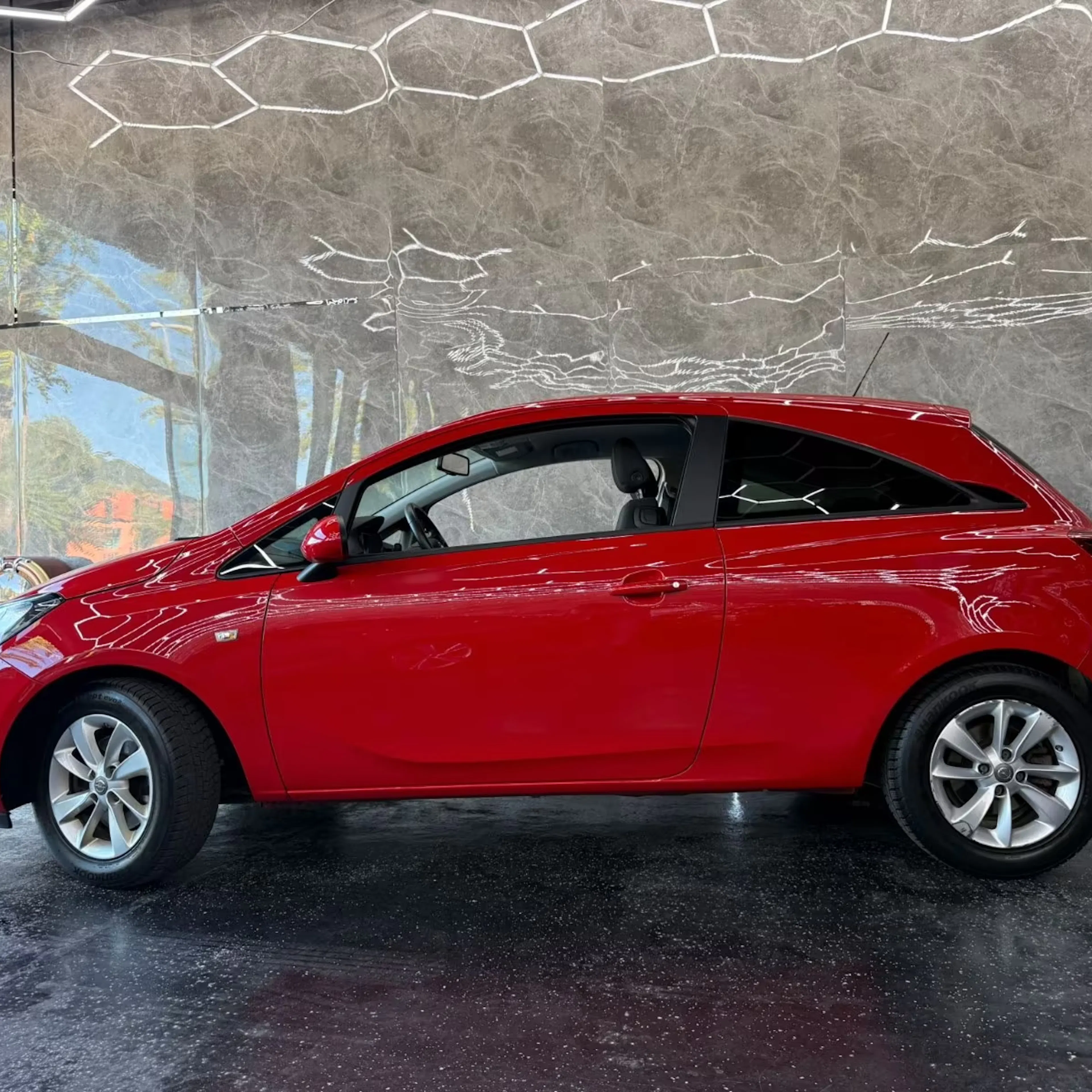 Ein roter Opel Corsa steht auf einer Verkaufsfläche.