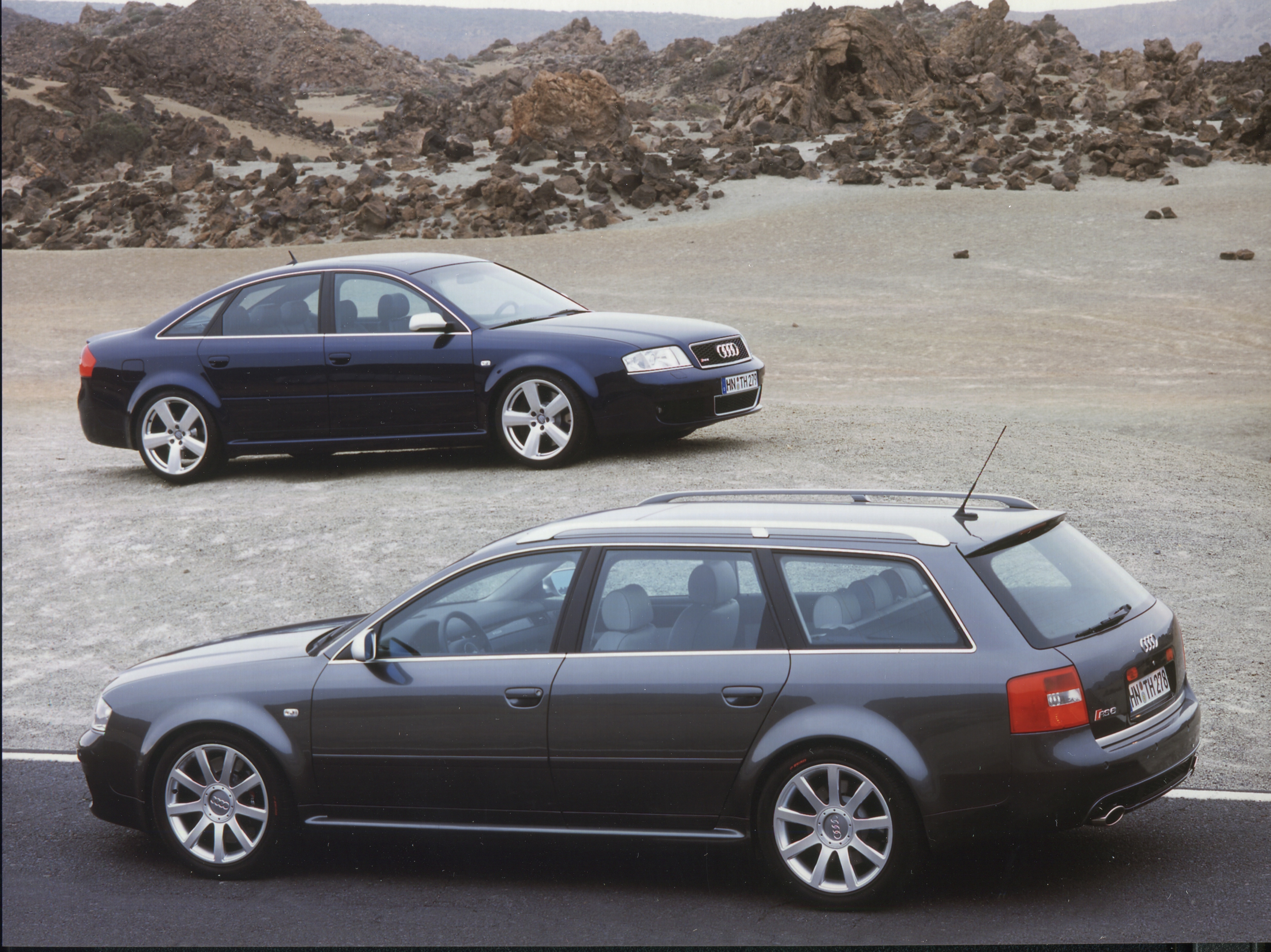 Dunkelblaue Audi-RS6-C5-Limousine und grauer RS6 Avant C5, seitlich fotografiert in einer Vulkanlandschaft.