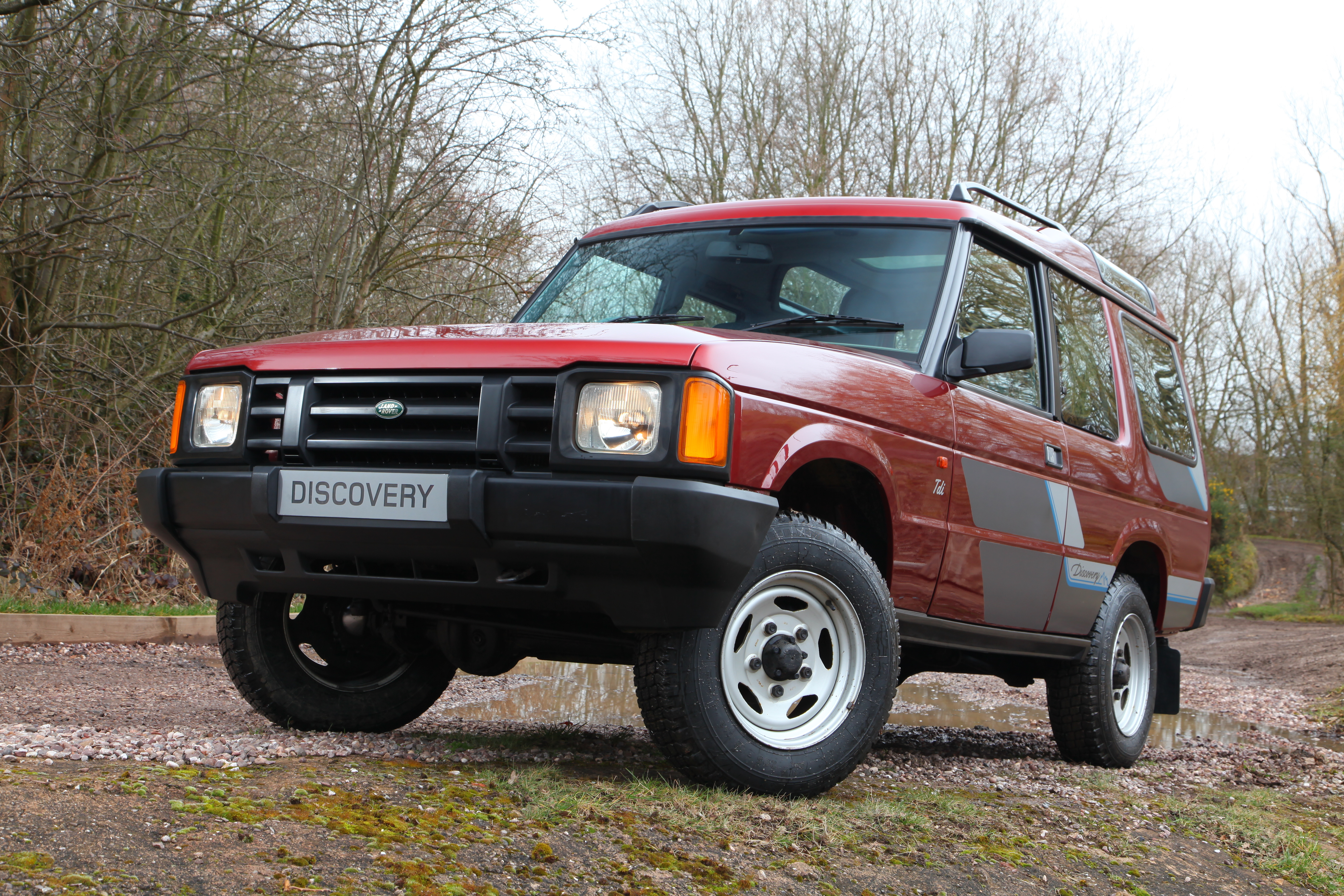 Dunkelroter Land Rover Discovery der ersten Generation in der Frontansicht auf unbefestigtem Untergrund.